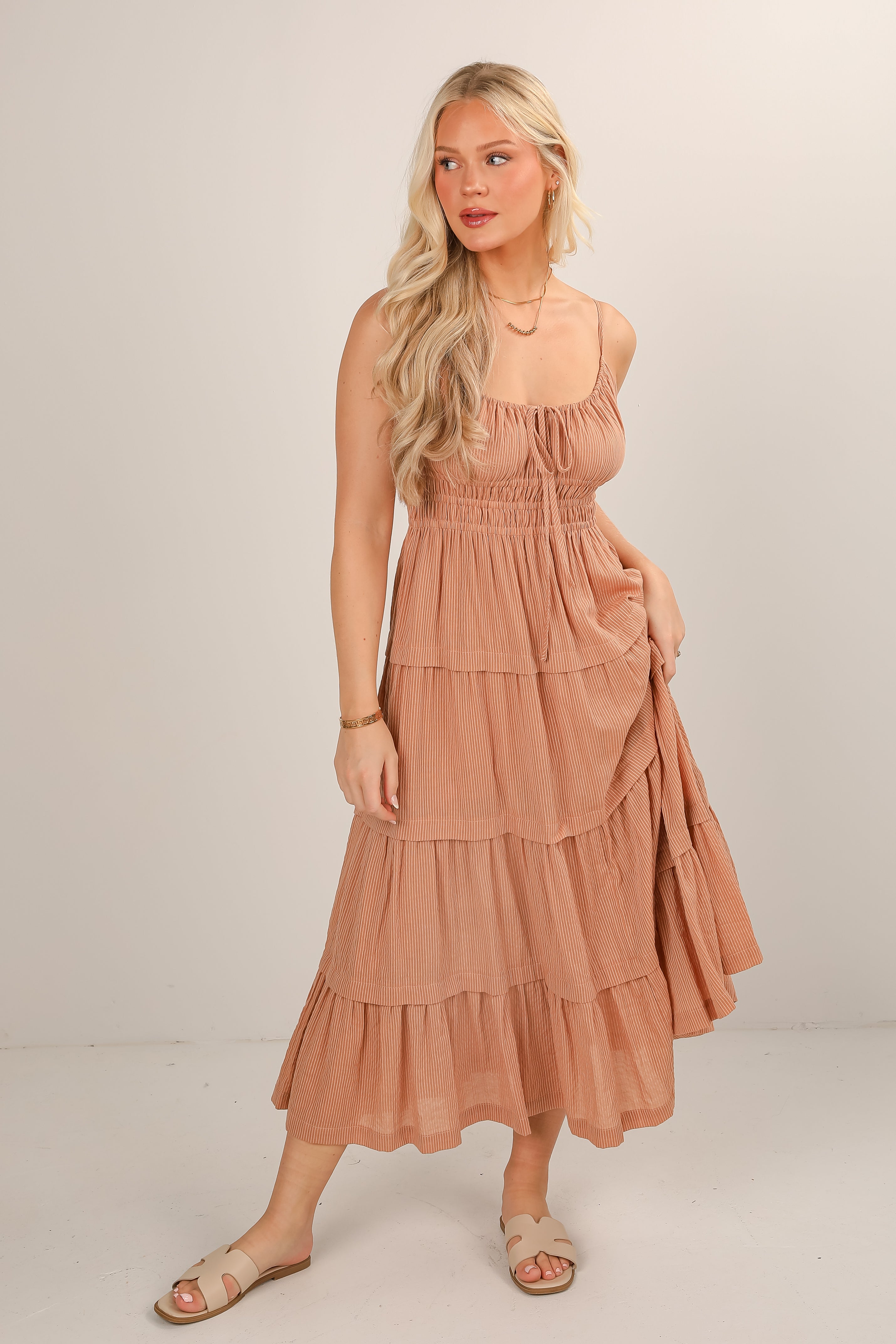 Woman wearing a tiered, sleeveless dress with a plain background