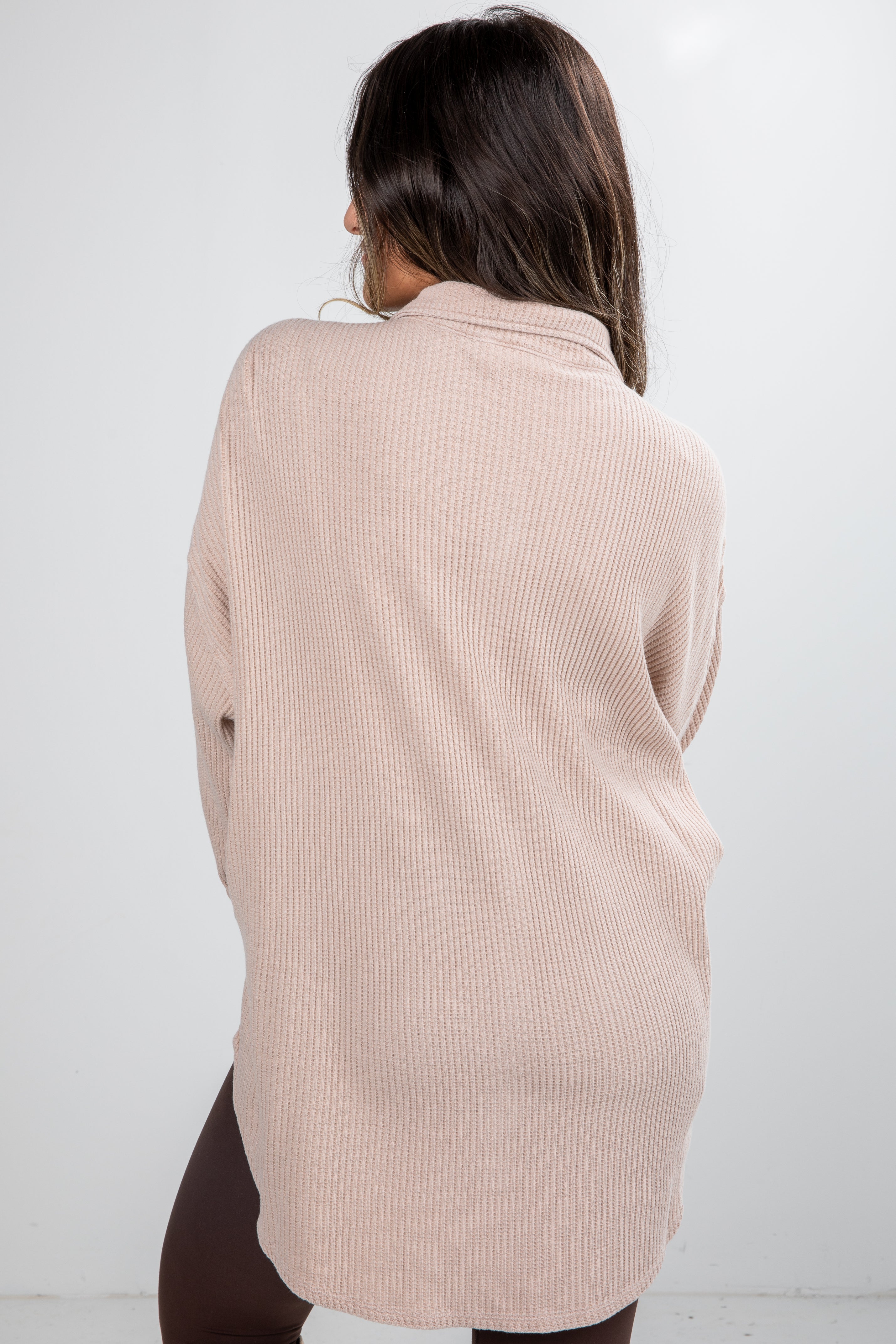 Woman wearing a beige ribbed sweater against a white background