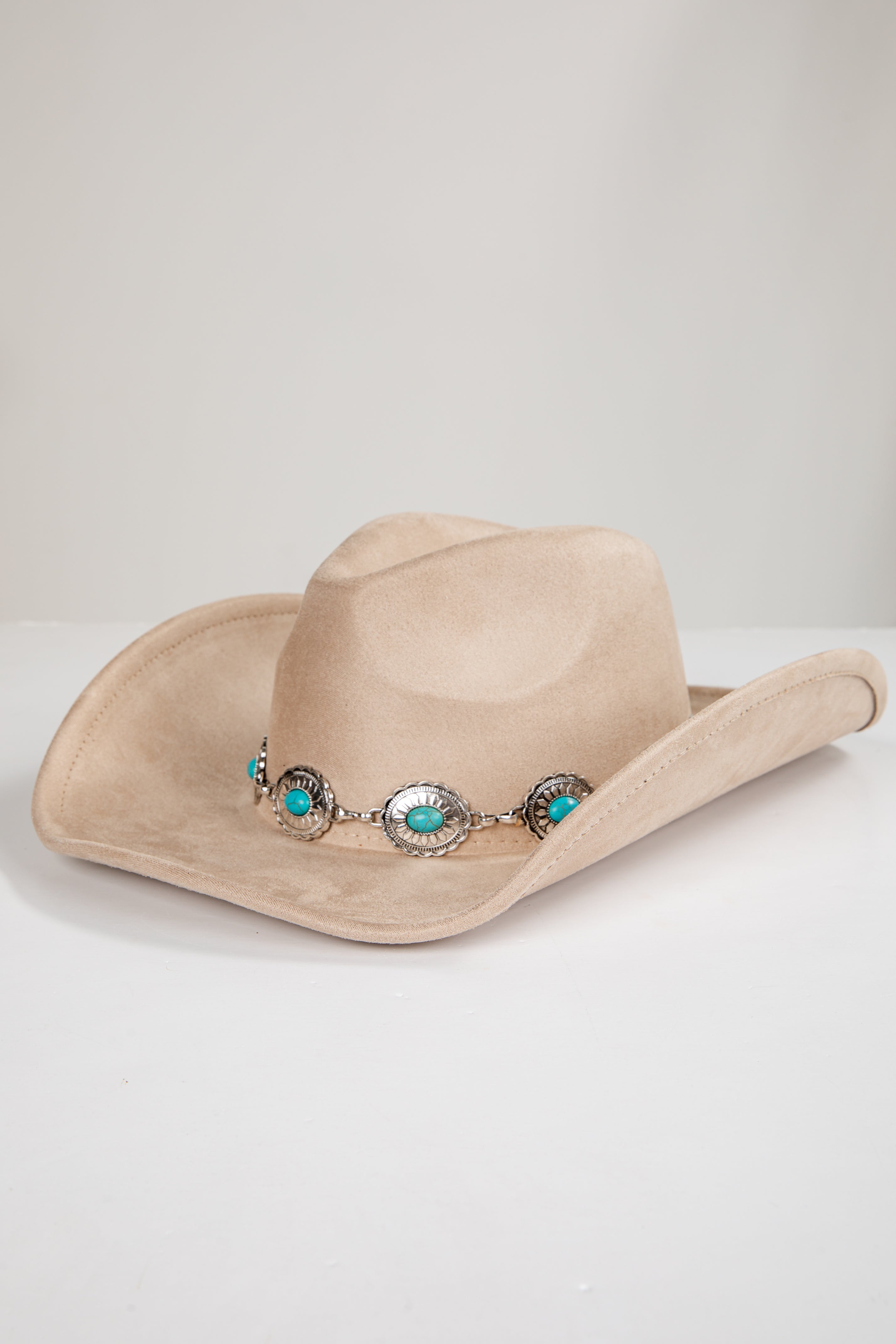 Beige cowboy hat with decorative band featuring turquoise stones on a light gray background