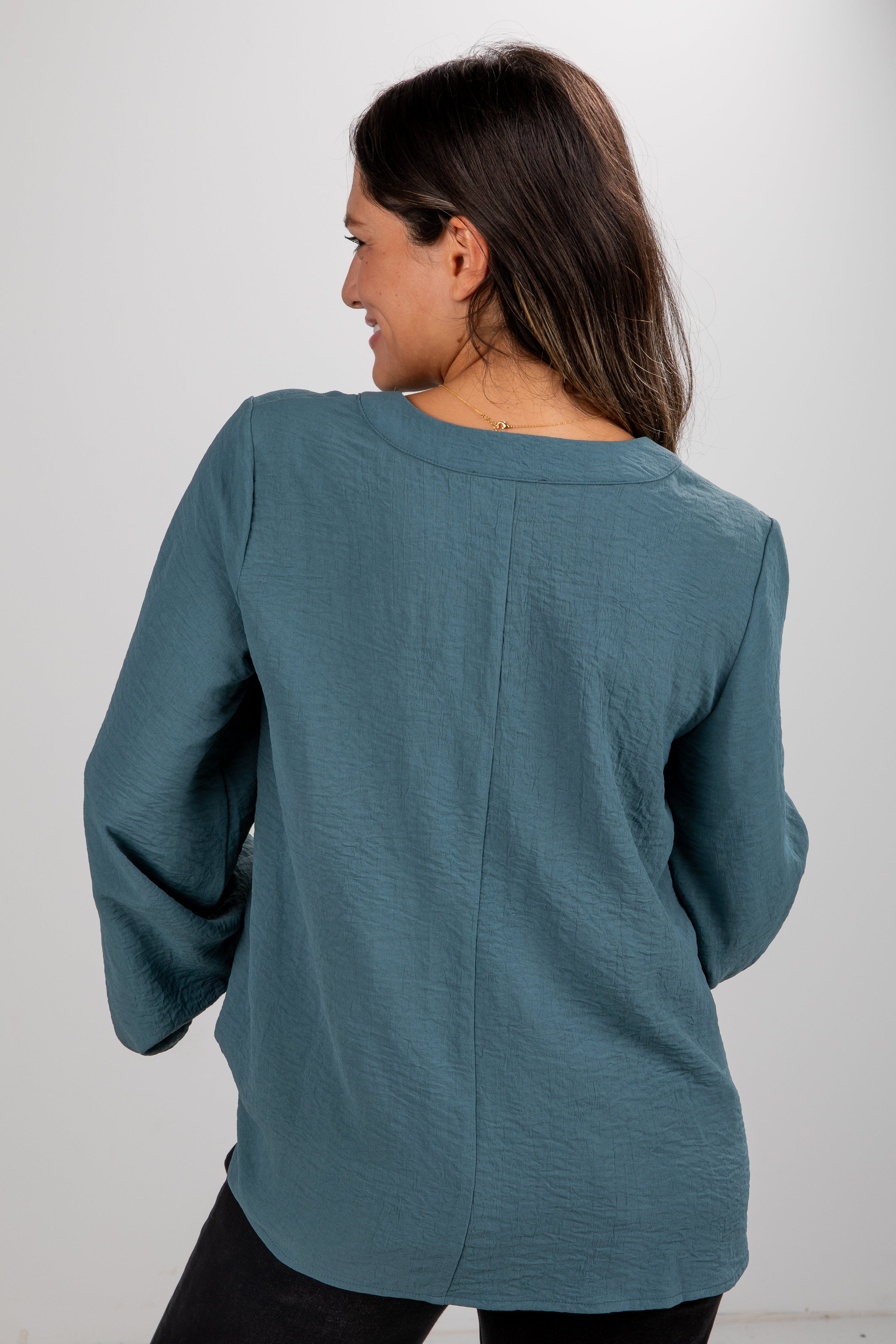 Woman wearing a teal sweater from behind on a white background
