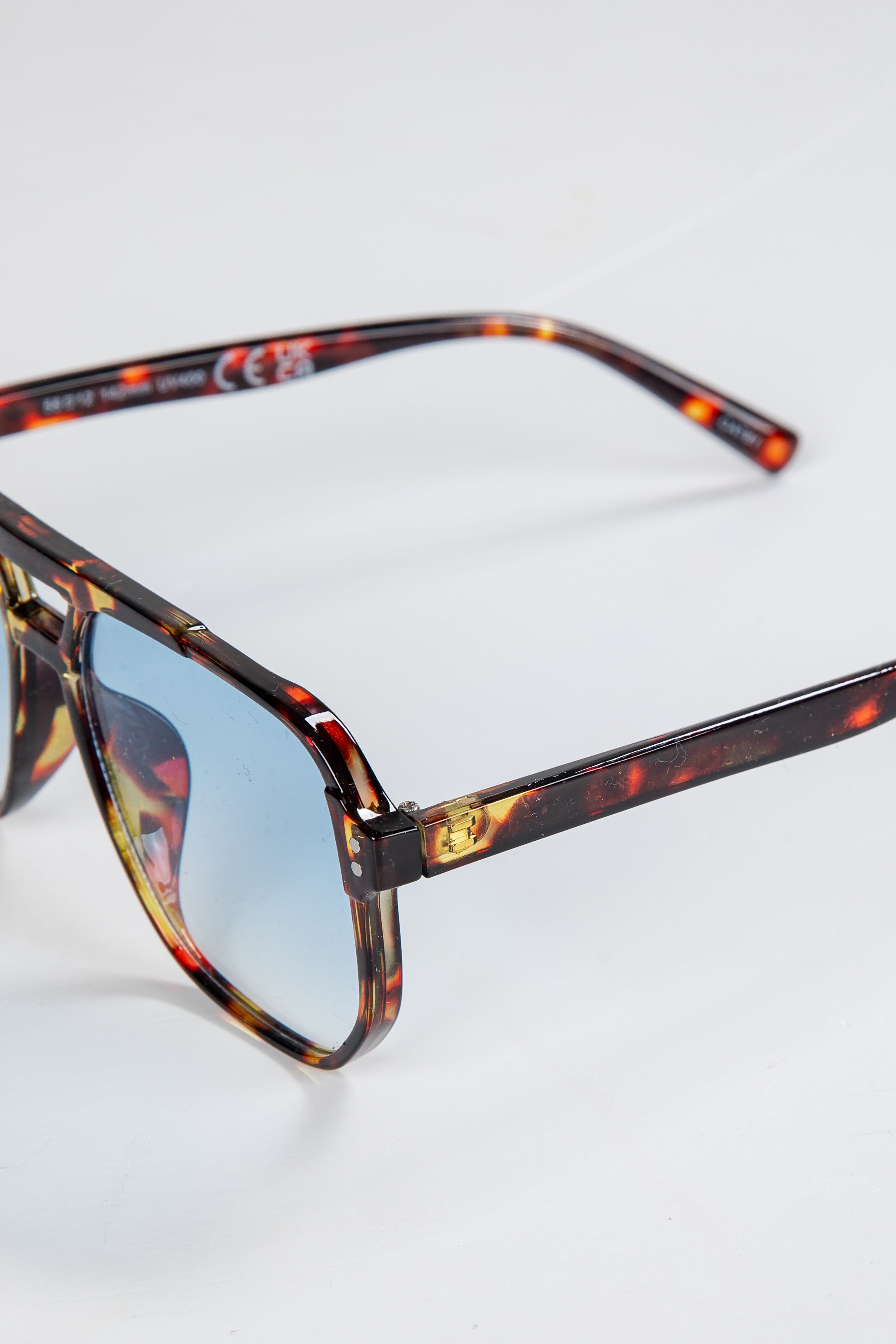 Sunglasses with tortoiseshell frame and blue-tinted lenses on a white background