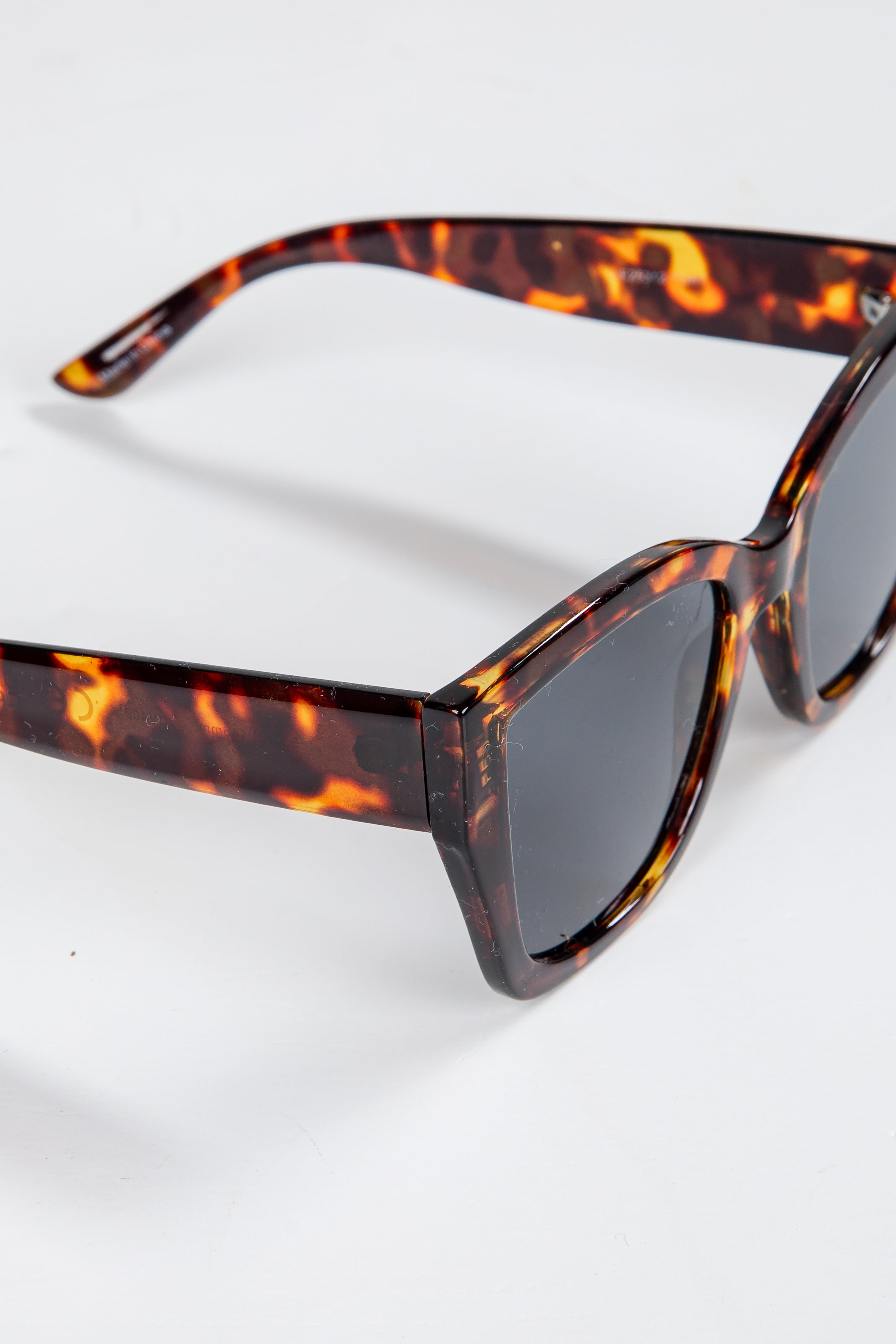 Sunglasses with tortoiseshell frame and dark lenses on a white background