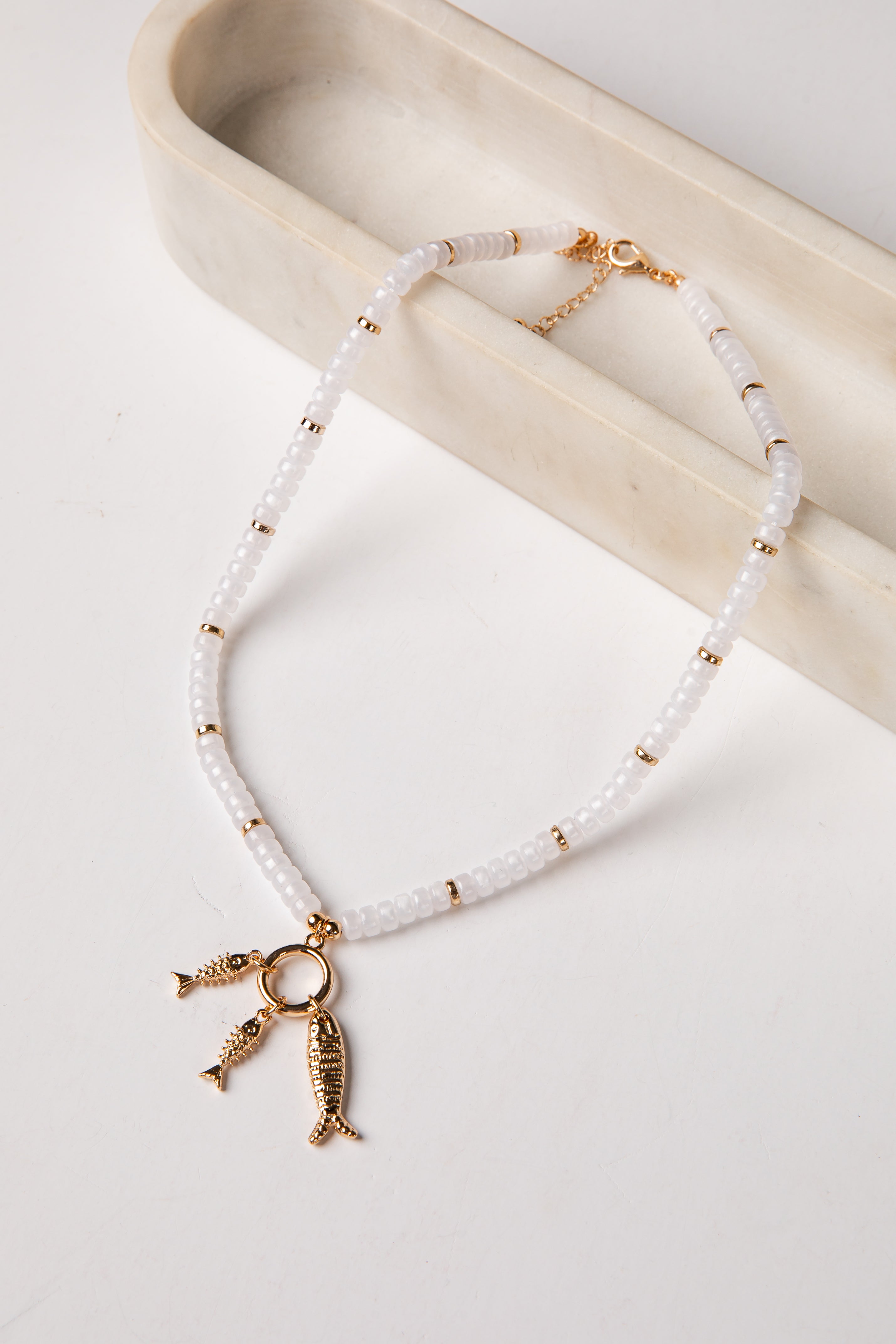 Necklace with fish charm on a white surface