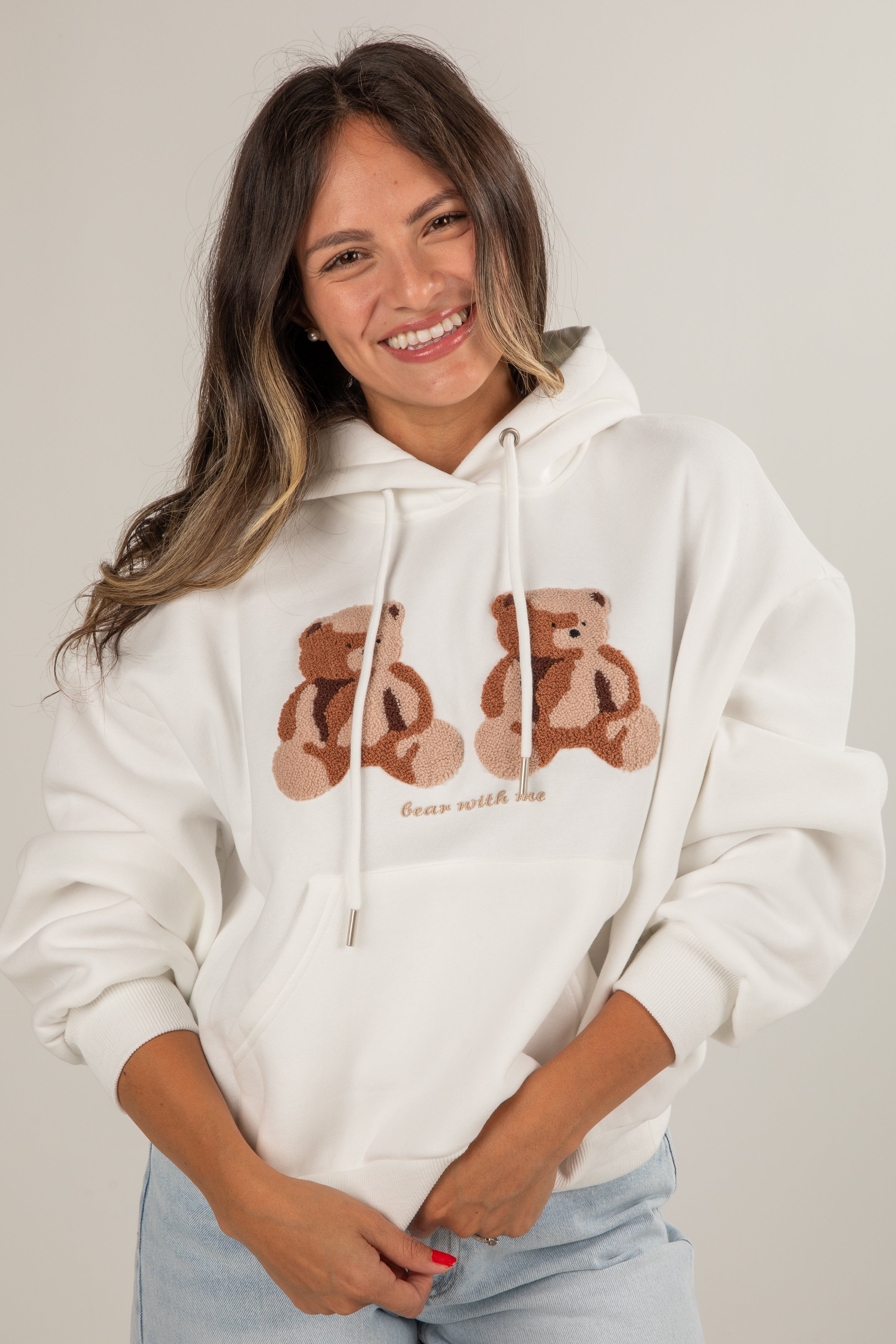 Woman wearing a white hoodie with bear graphics on a plain background
