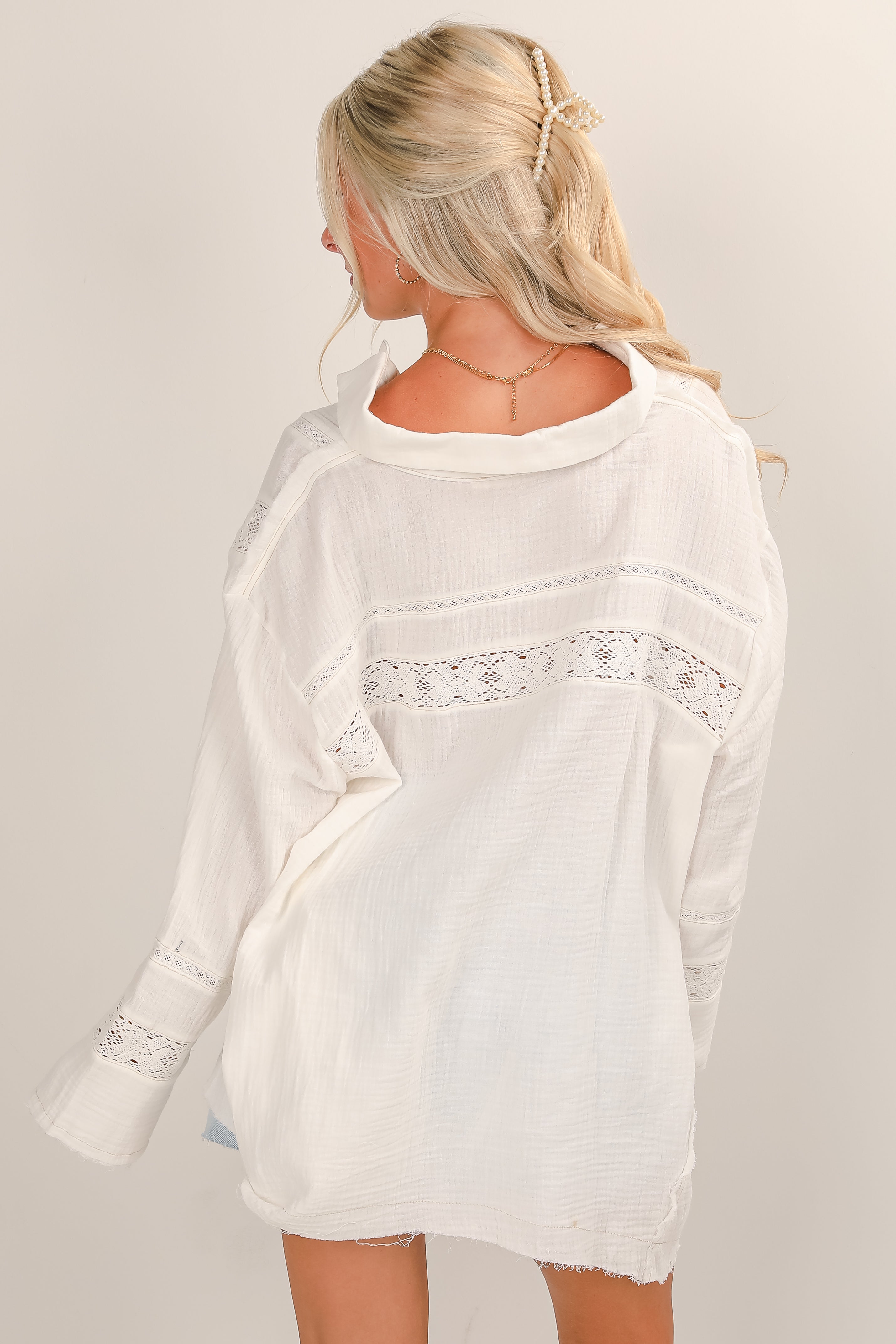 Woman wearing a white lace-trimmed dress against a plain background