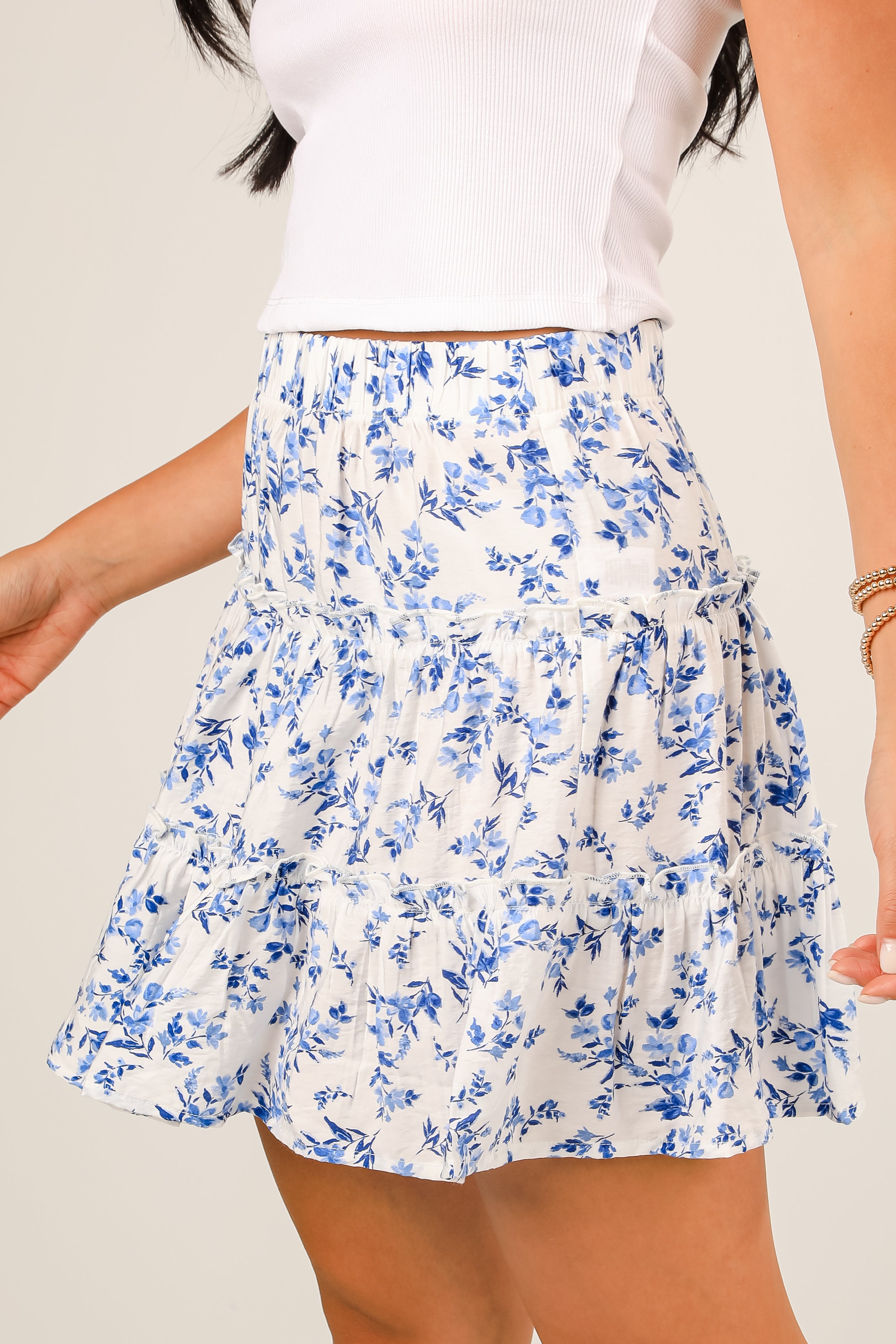 White skirt with blue floral pattern worn by a person on a plain background