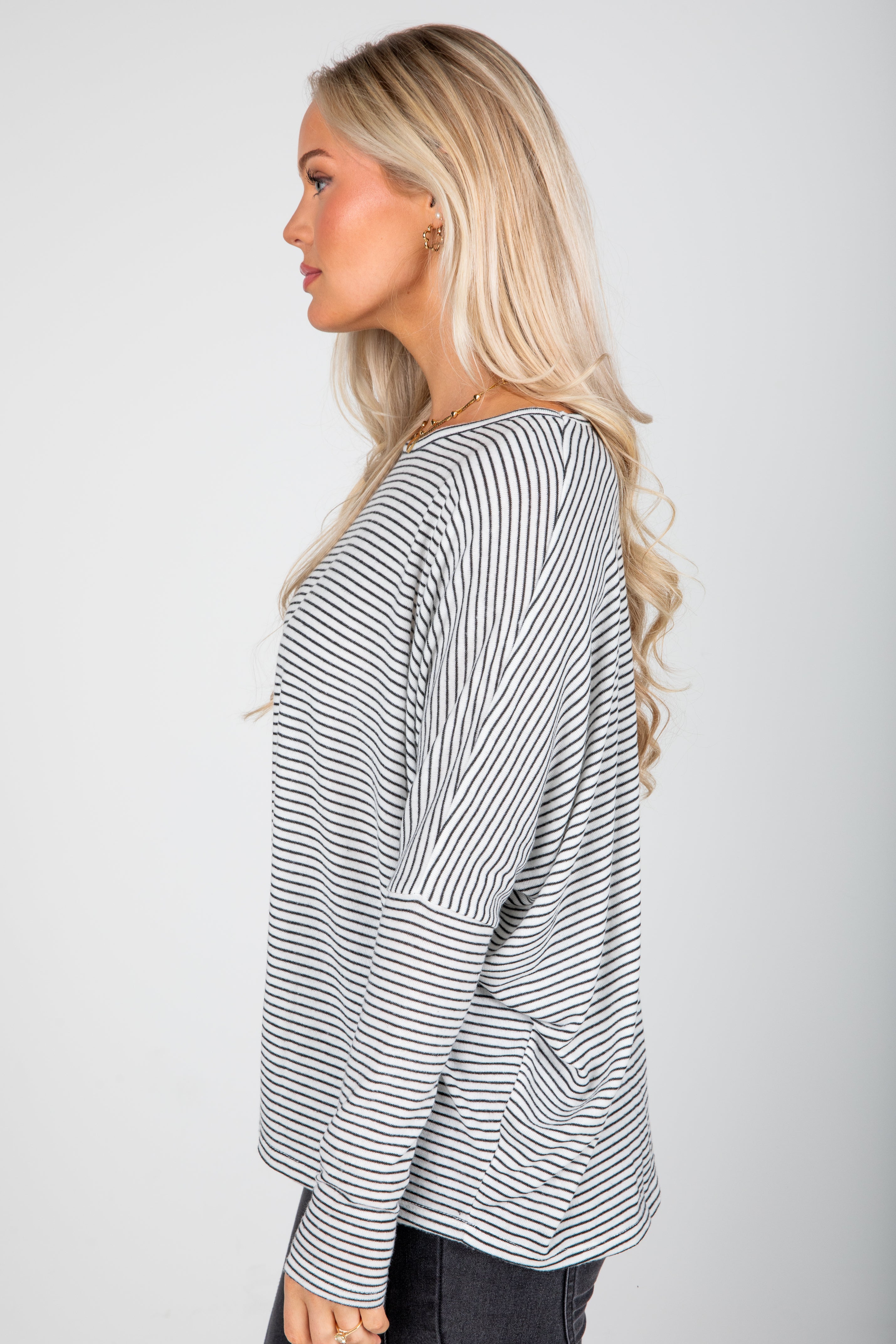 Woman wearing a black and white striped long-sleeve top on a plain background