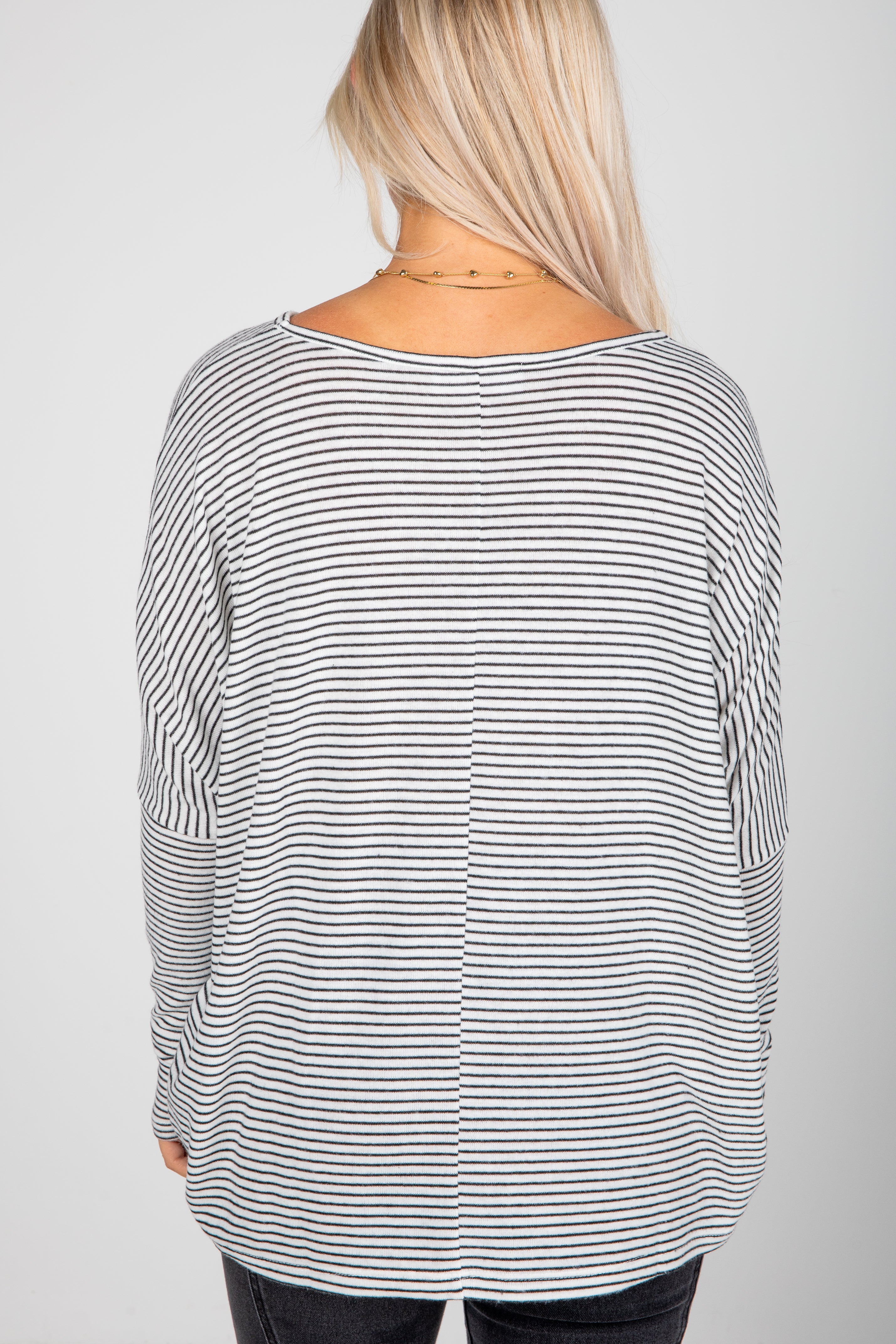 Person wearing a black and white striped long-sleeve top on a plain background