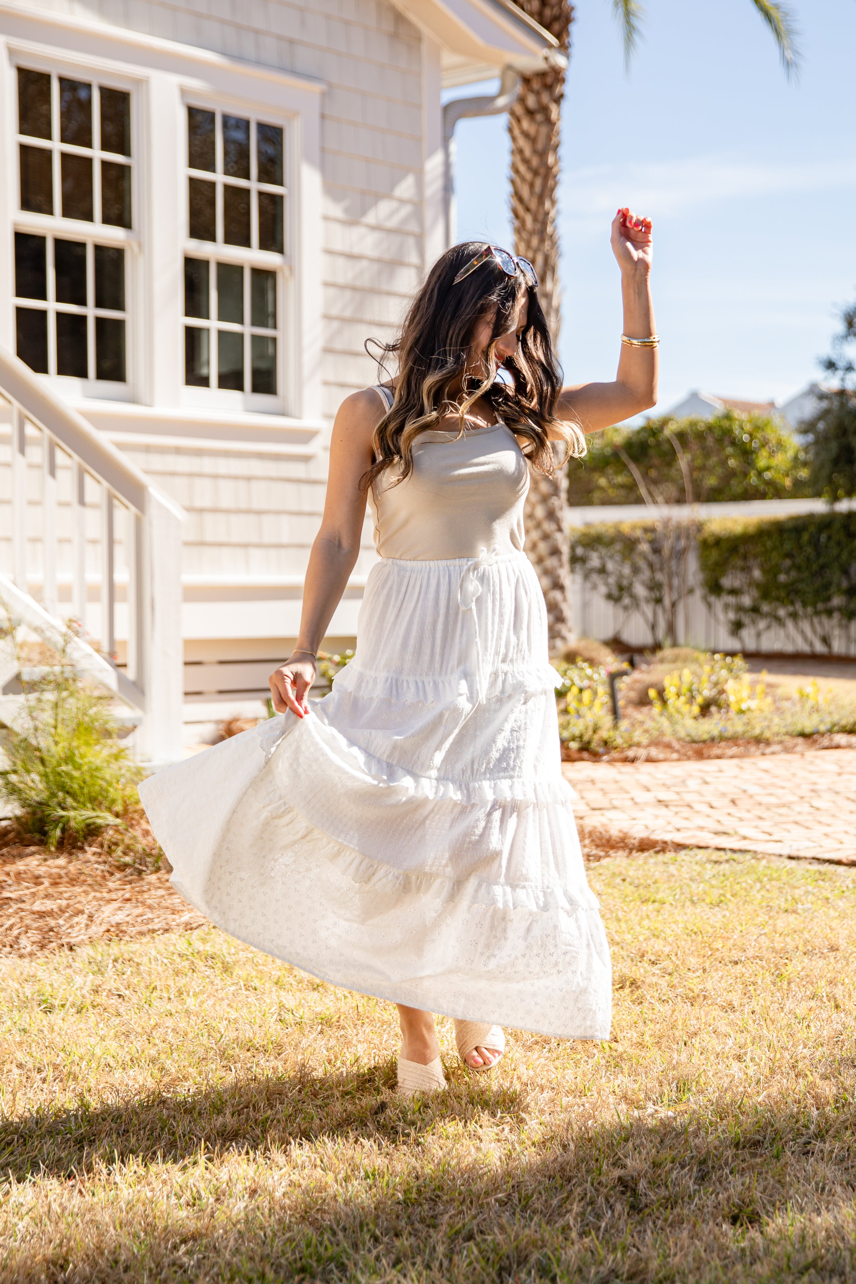 Woman in a white dress standing outdoors near a house
