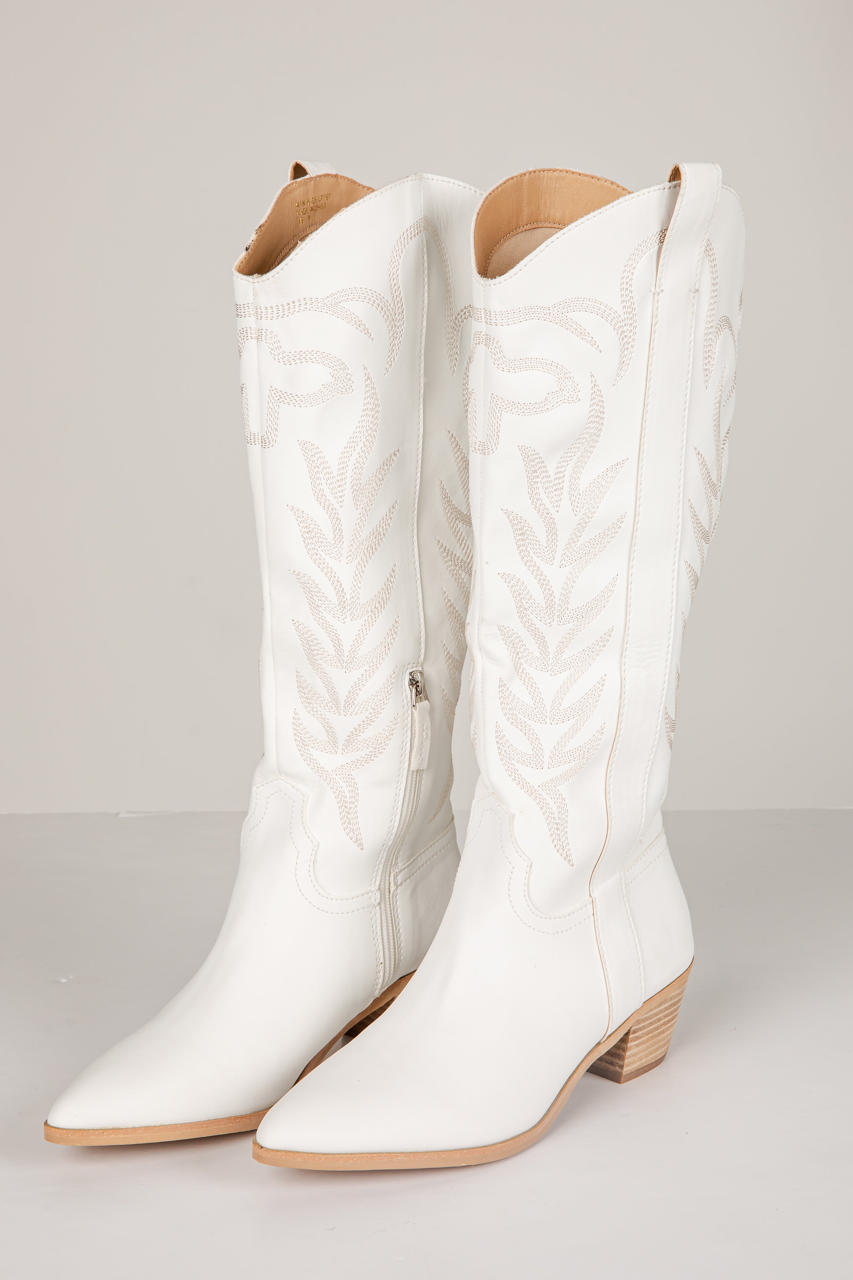 White quilted knee-high boots on a light gray background