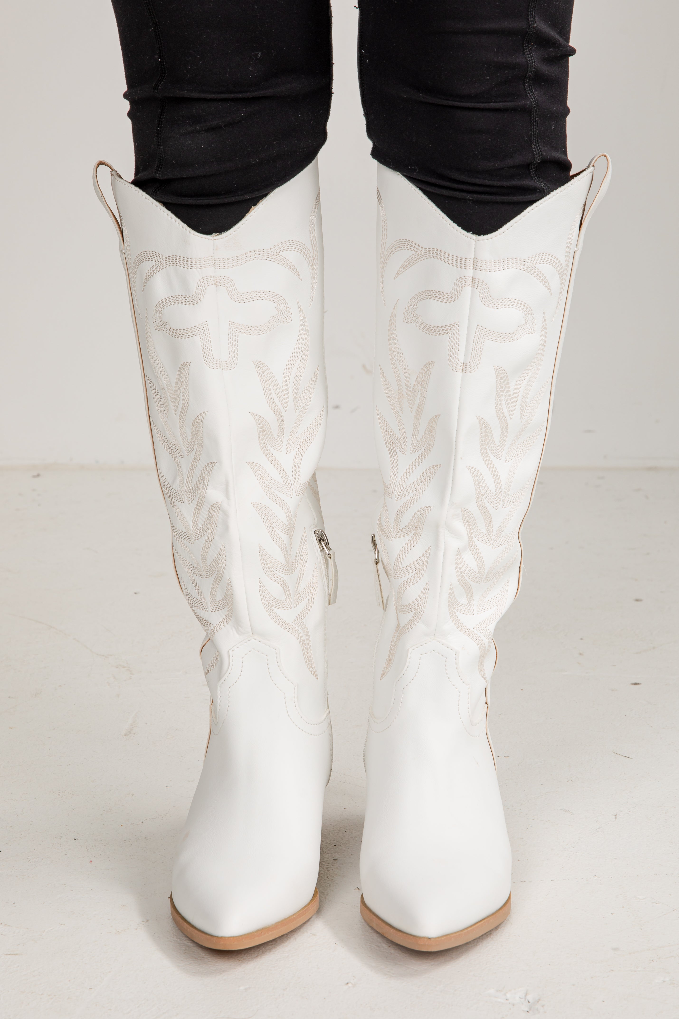 White embroidered knee-high boots on a white background