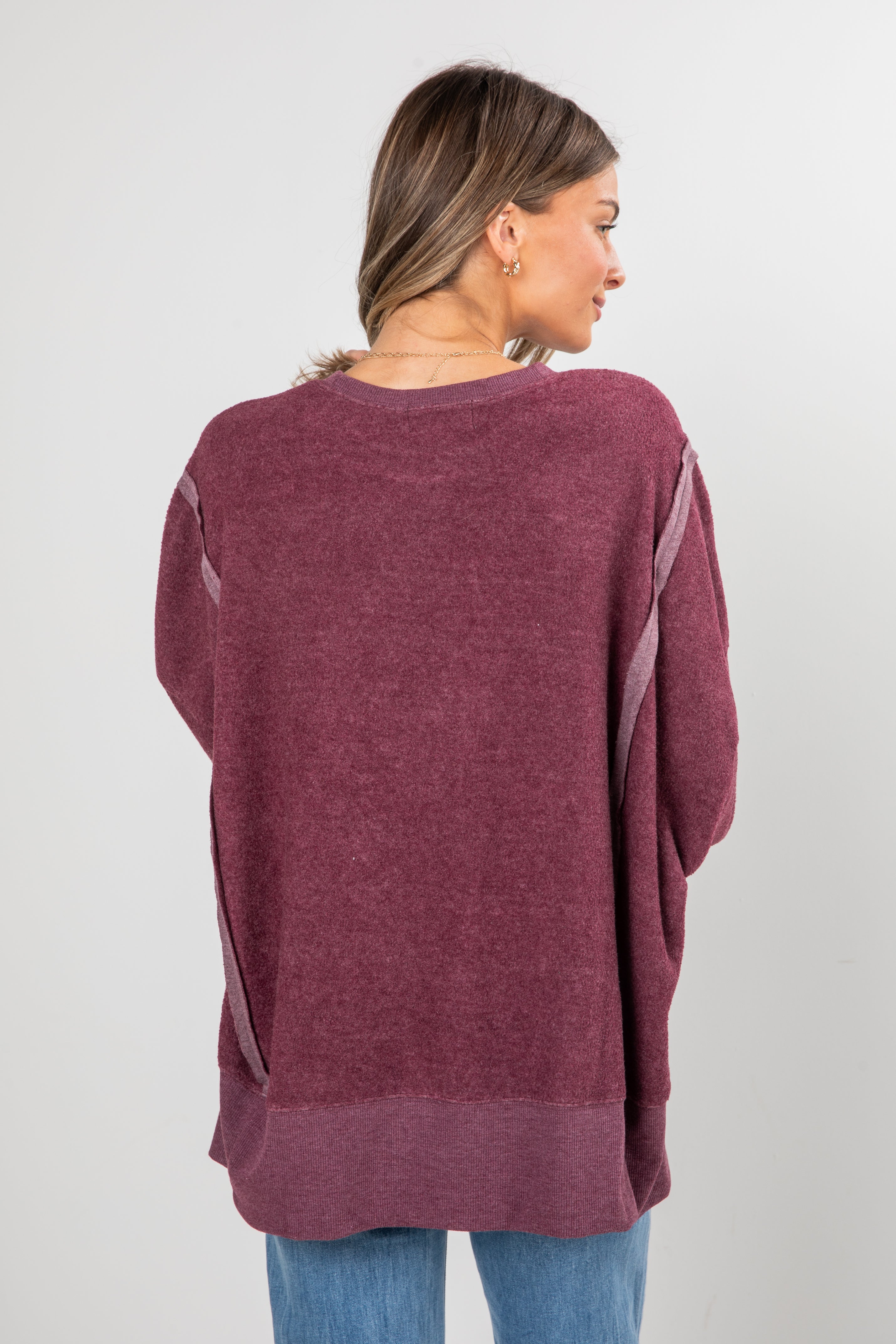 Woman wearing a maroon sweater with a plain background