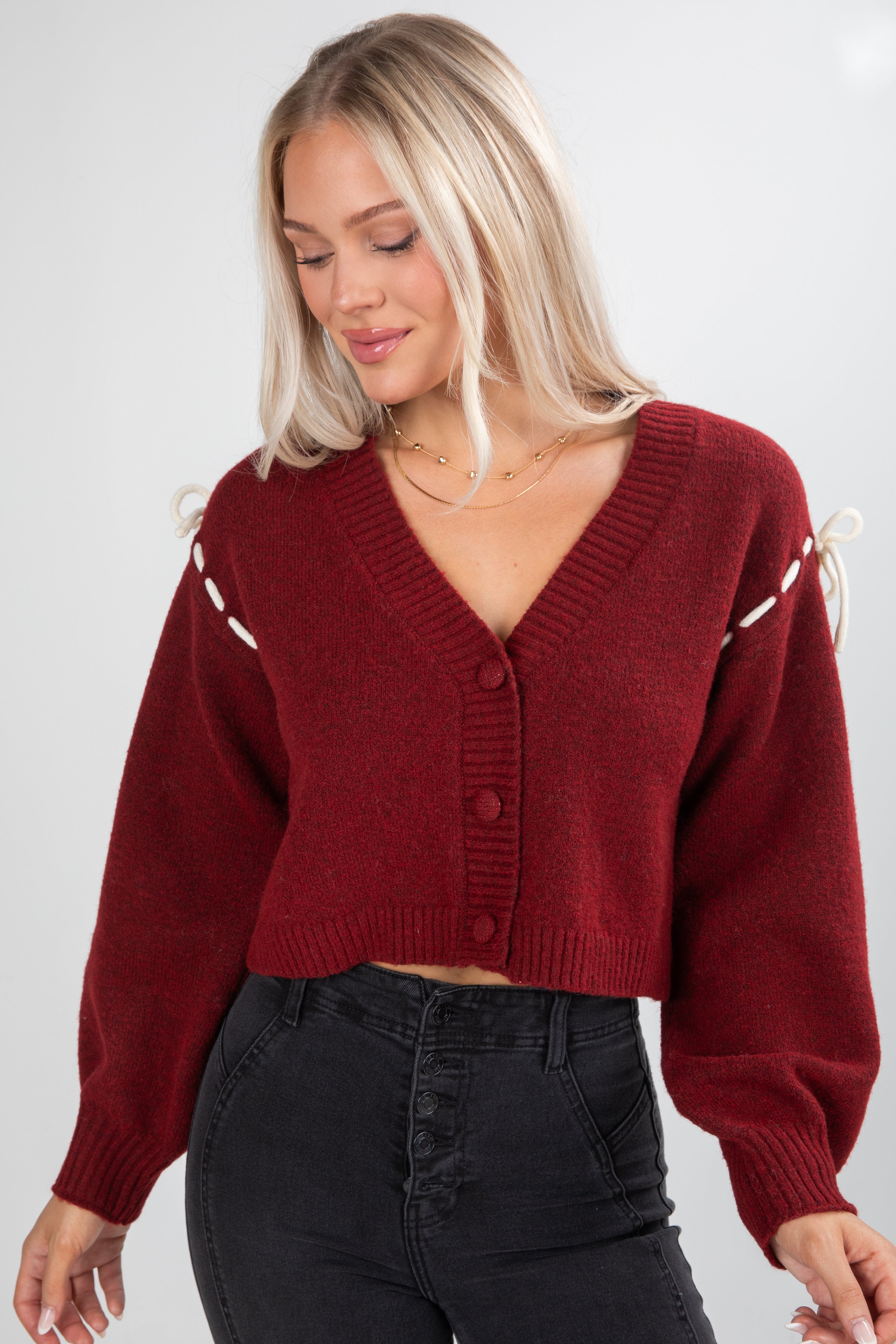Woman wearing a red sweater with white accents on a plain background