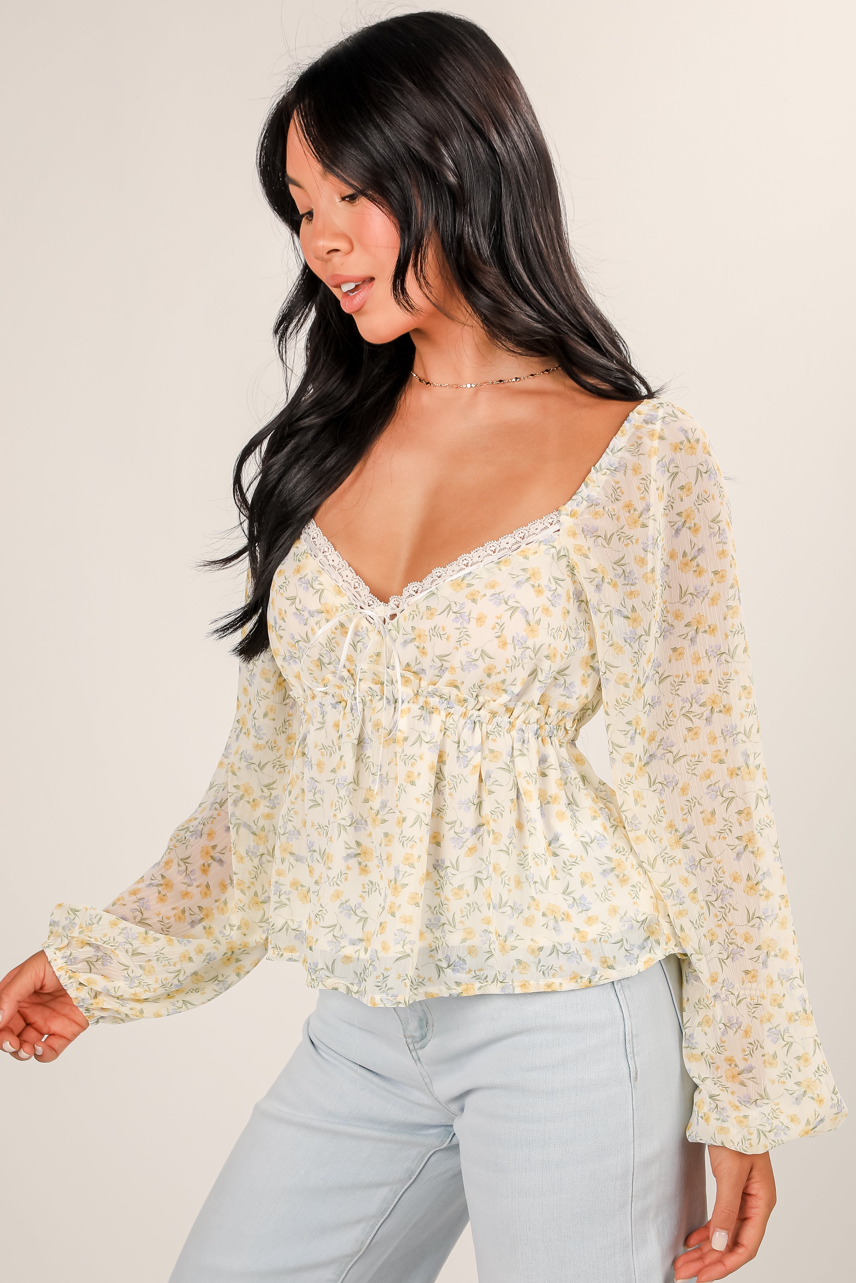 Woman wearing a floral blouse with long sleeves against a plain background