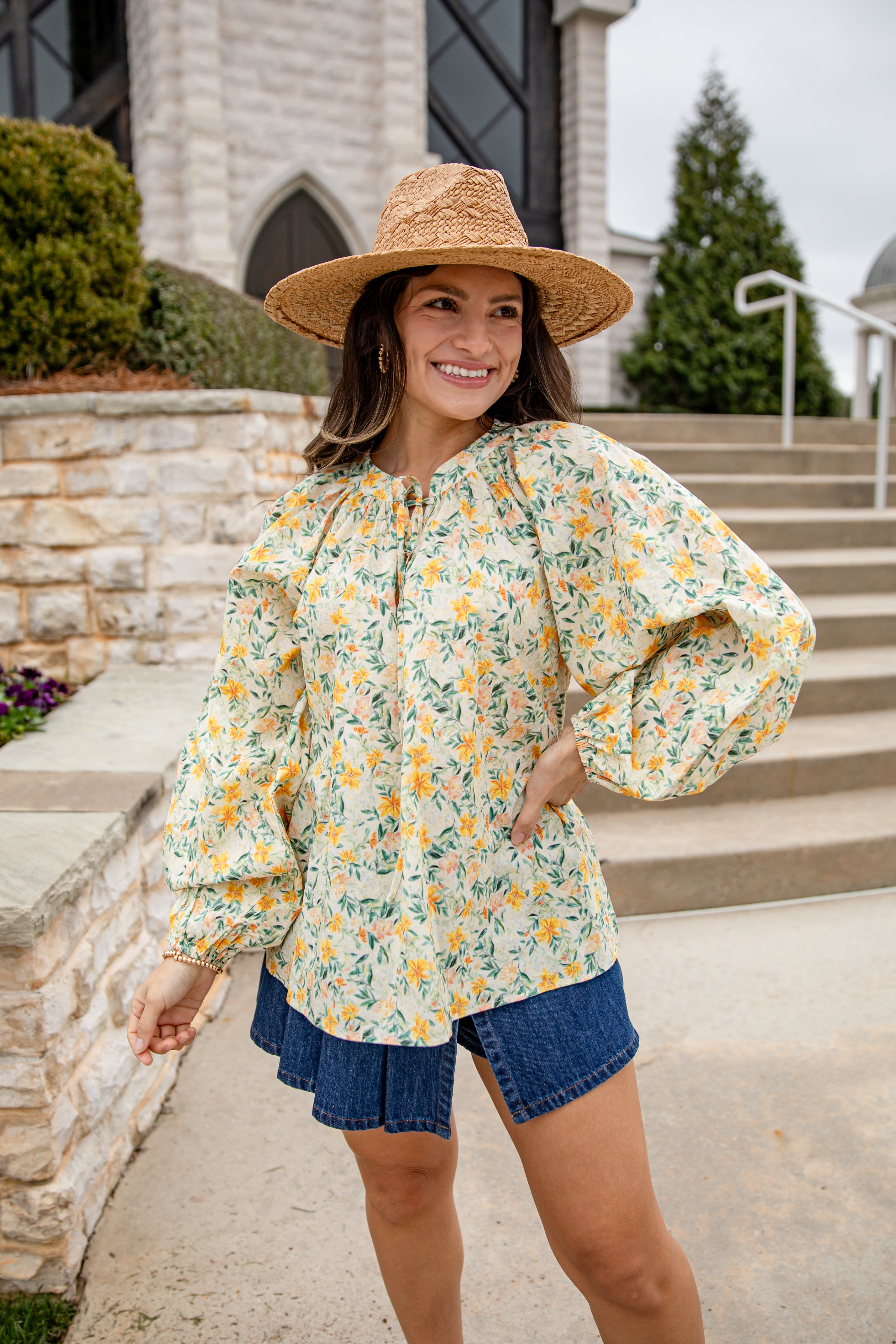 Woman wearing a floral blouse and straw hat outdoors
