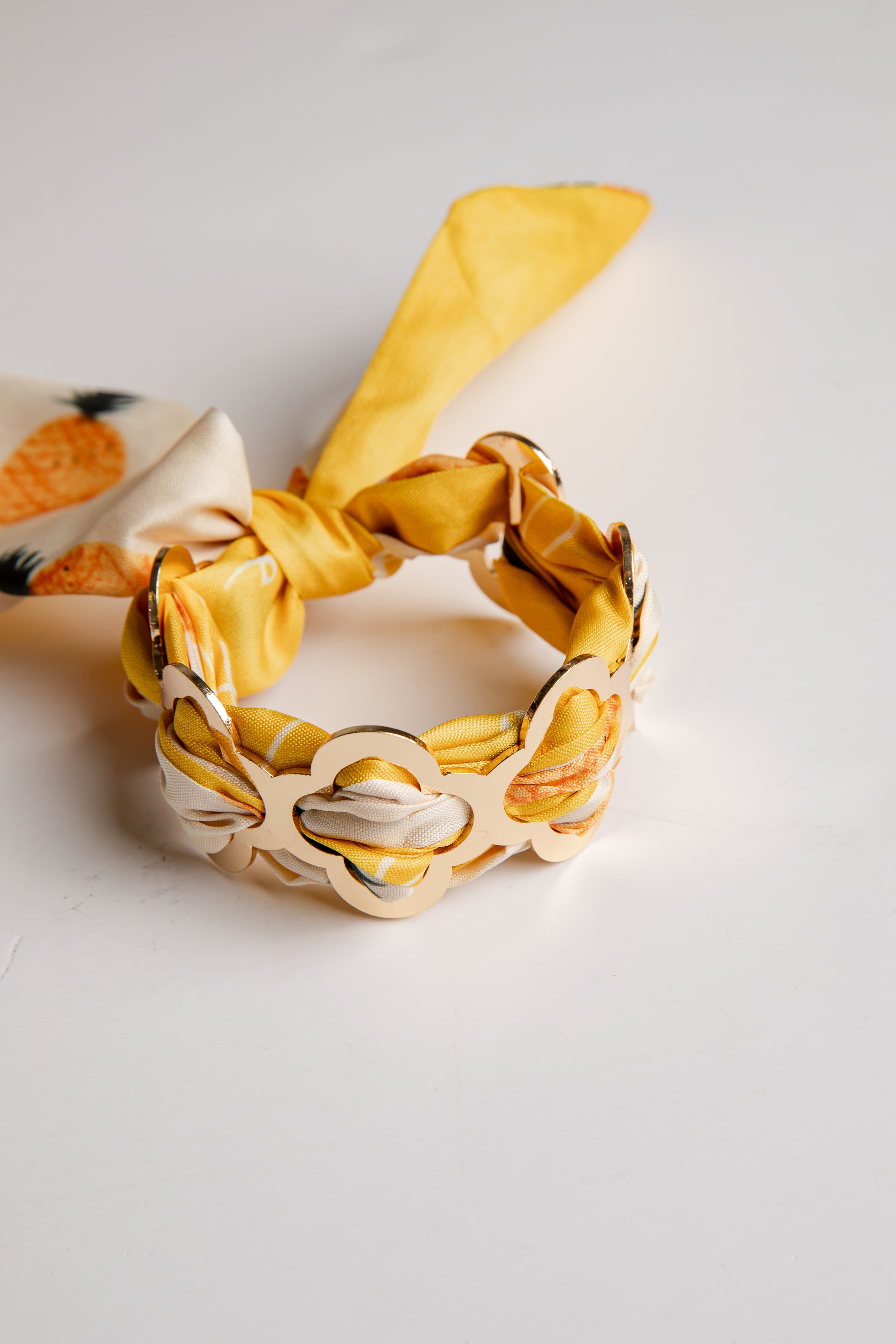 Yellow and beige headband with a decorative bow on a light gray background