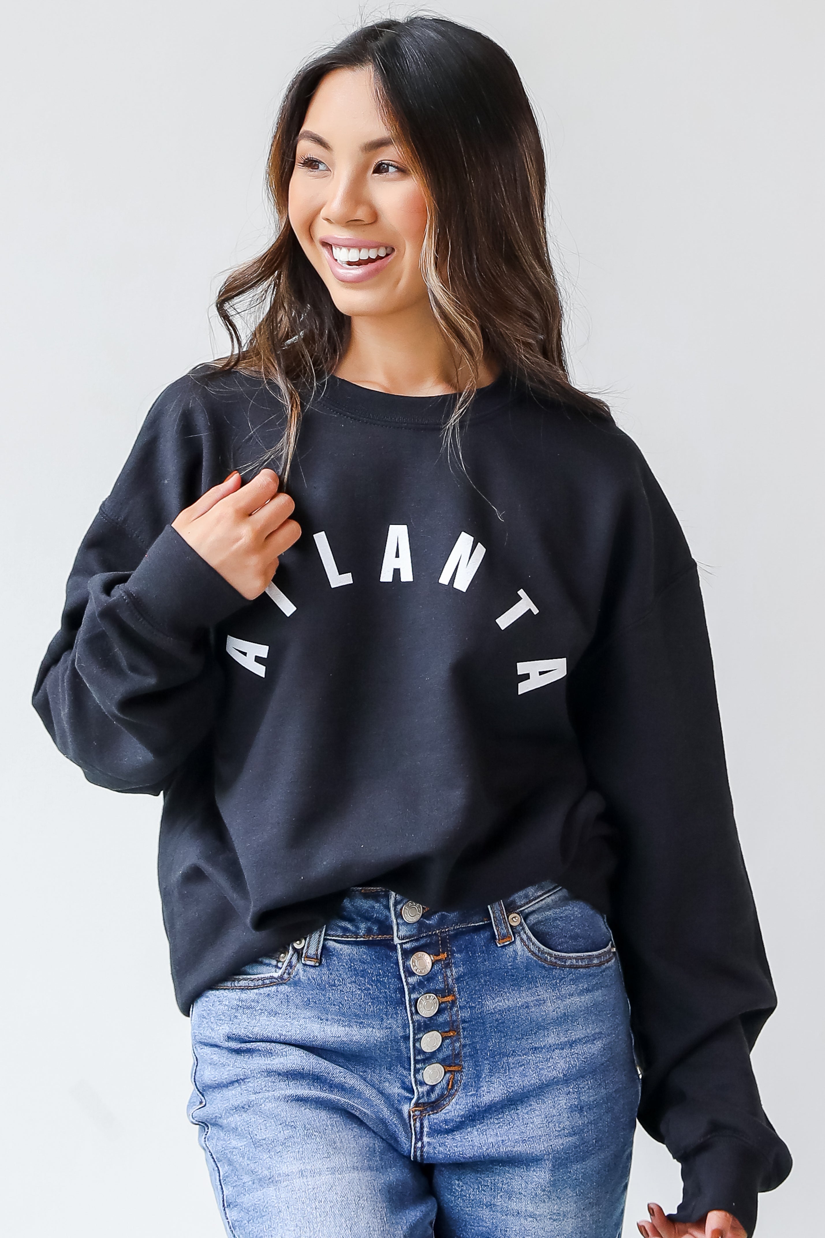 This comfy sweatshirt is designed with a soft and stretchy knit with a fleece interior. It features a crew neckline, long sleeves, a relaxed fit, and the word "Atlanta" on the front.