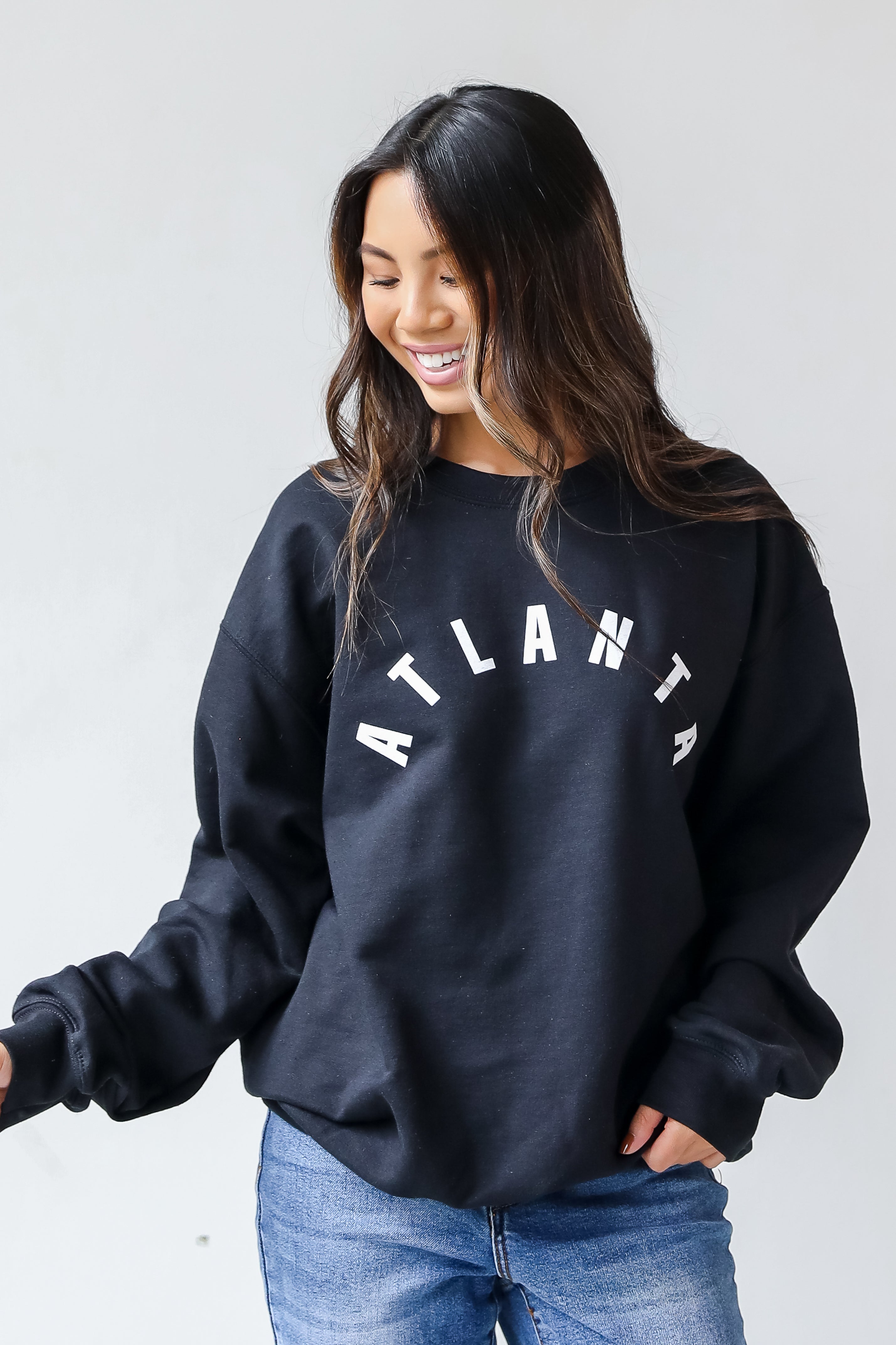 This comfy sweatshirt is designed with a soft and stretchy knit with a fleece interior. It features a crew neckline, long sleeves, a relaxed fit, and the word "Atlanta" on the front.