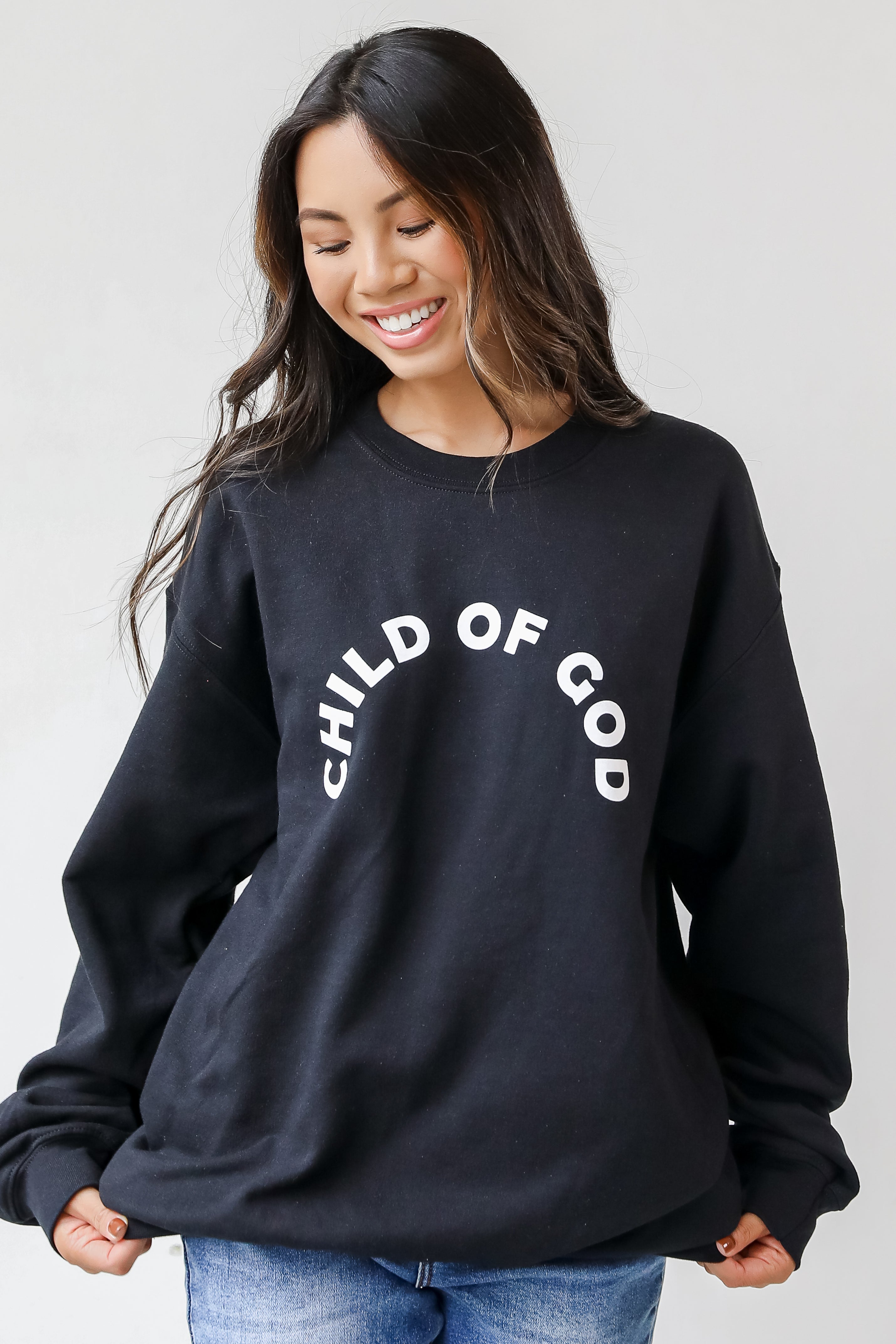 This comfy sweatshirt is designed with a soft and stretchy knit with a fleece interior. It features a crew neckline, long sleeves, a relaxed fit, and the words "Child Of God" on the front.