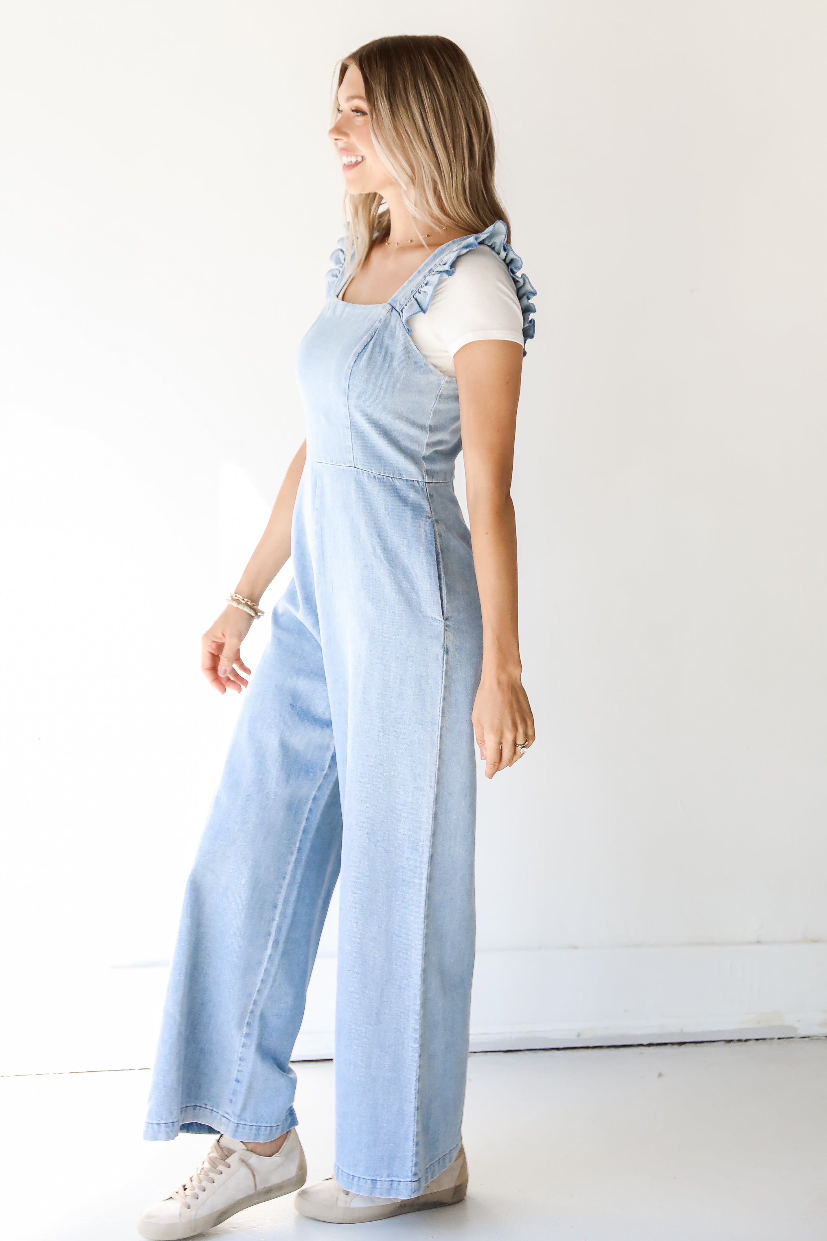 side view of a light wash denim jumpsuit