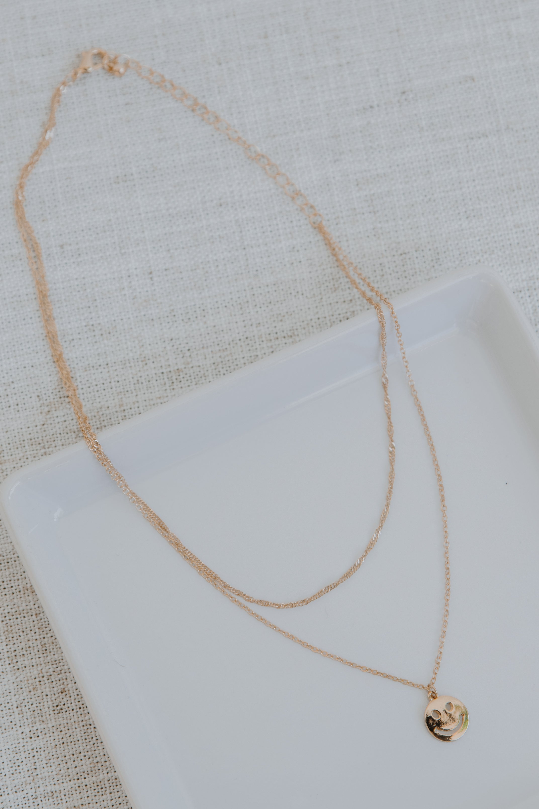 Gold Layered Smiley Face Necklace flat lay