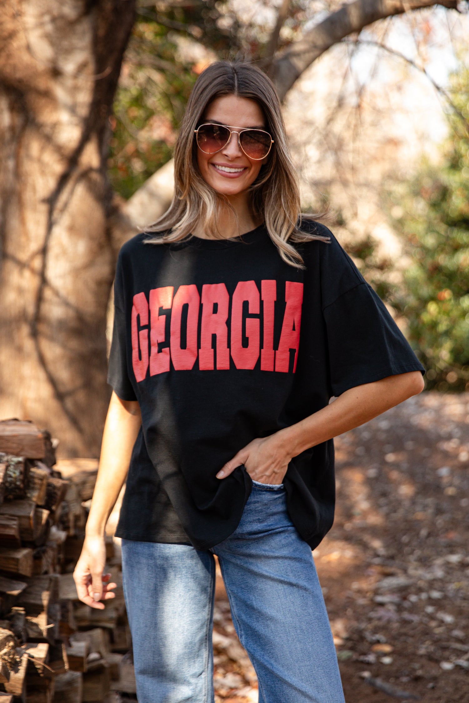 Women wearing sunglasses, with a black shirt that says Georgia and jeans. 