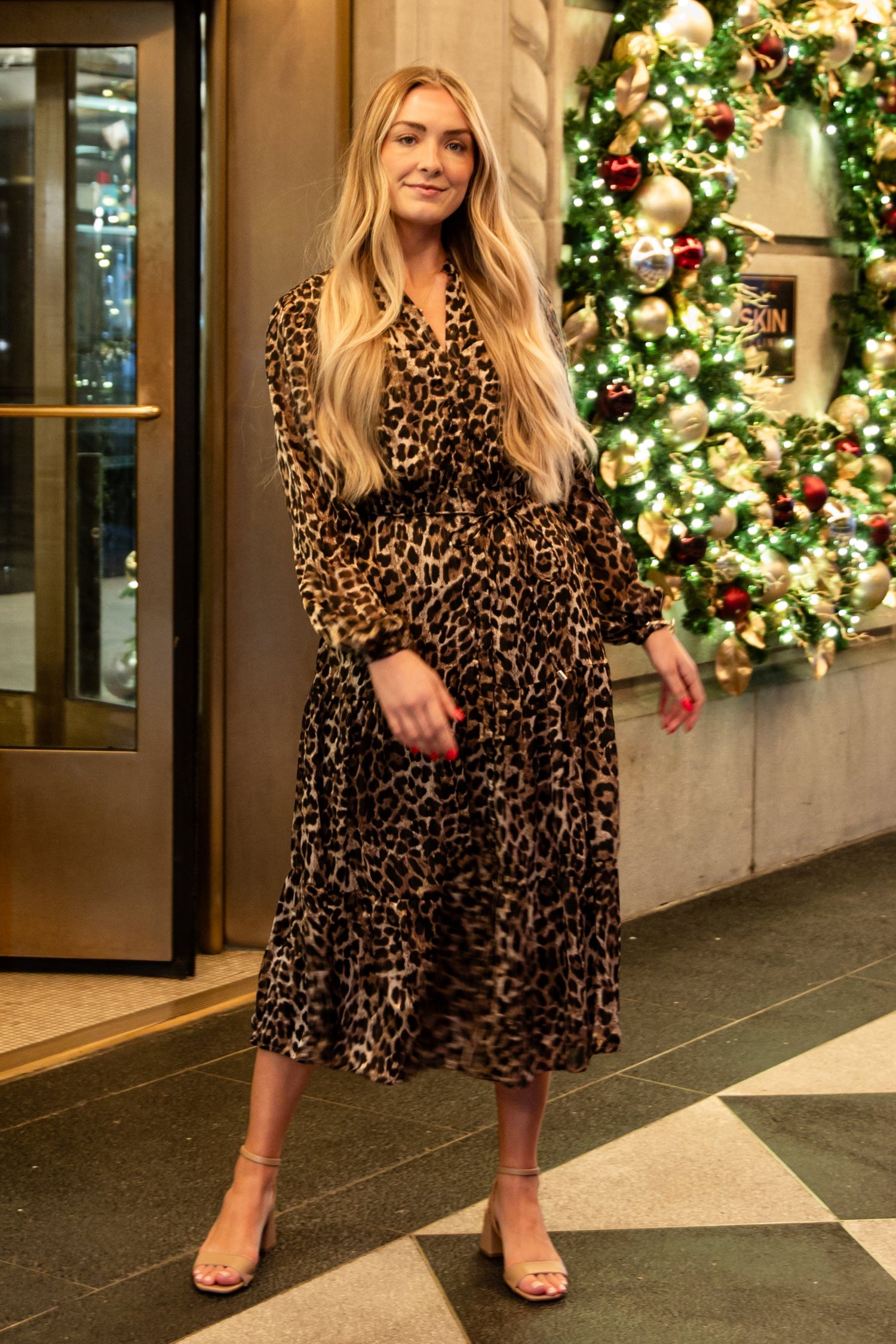 Woman standing in a decorated lobby with Christmas wreaths and lights.