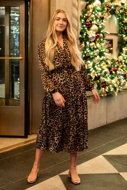 Woman standing in a decorated lobby with Christmas wreaths and lights.