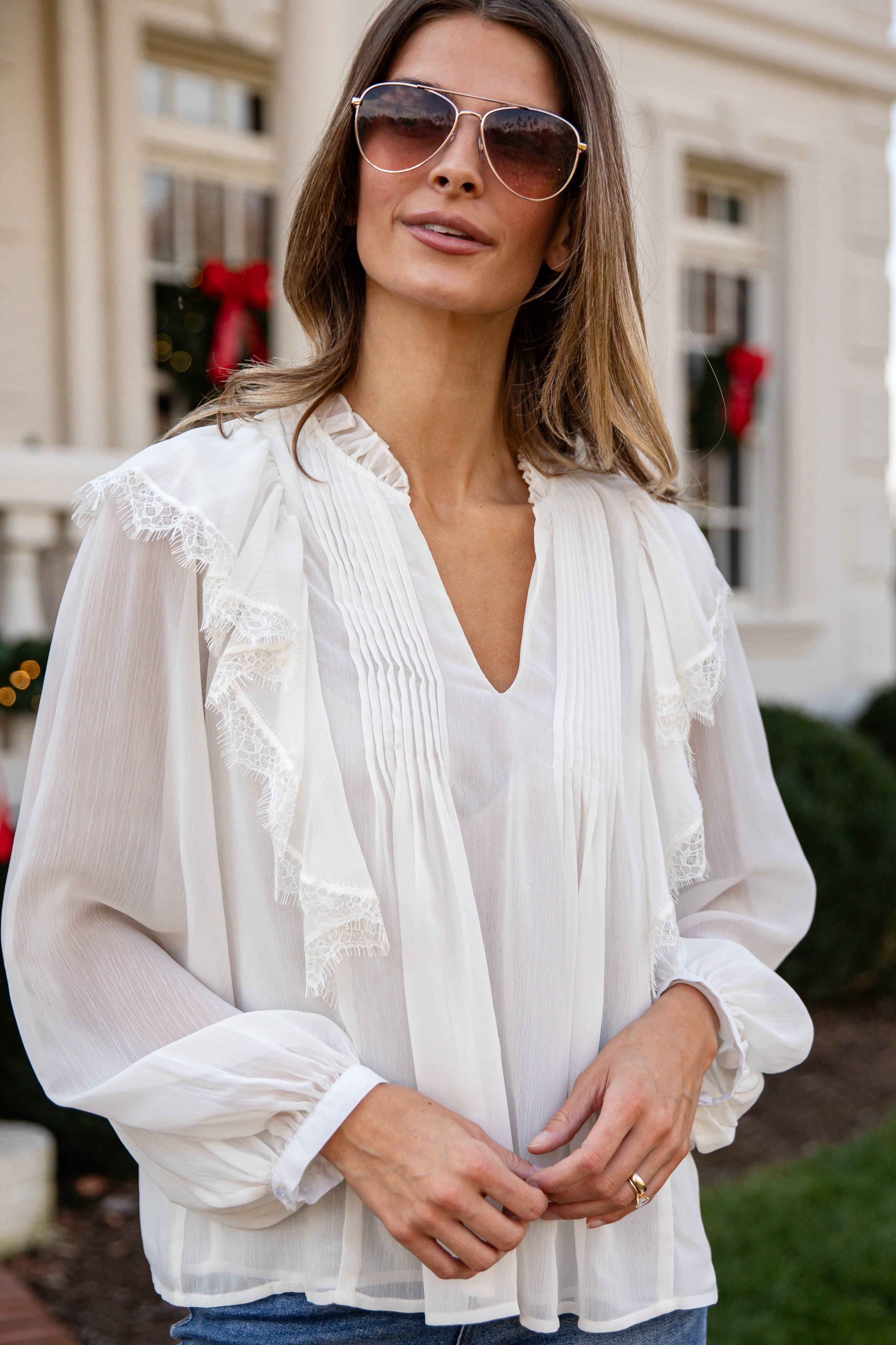Woman wearing a white blouse and sunglasses outdoors