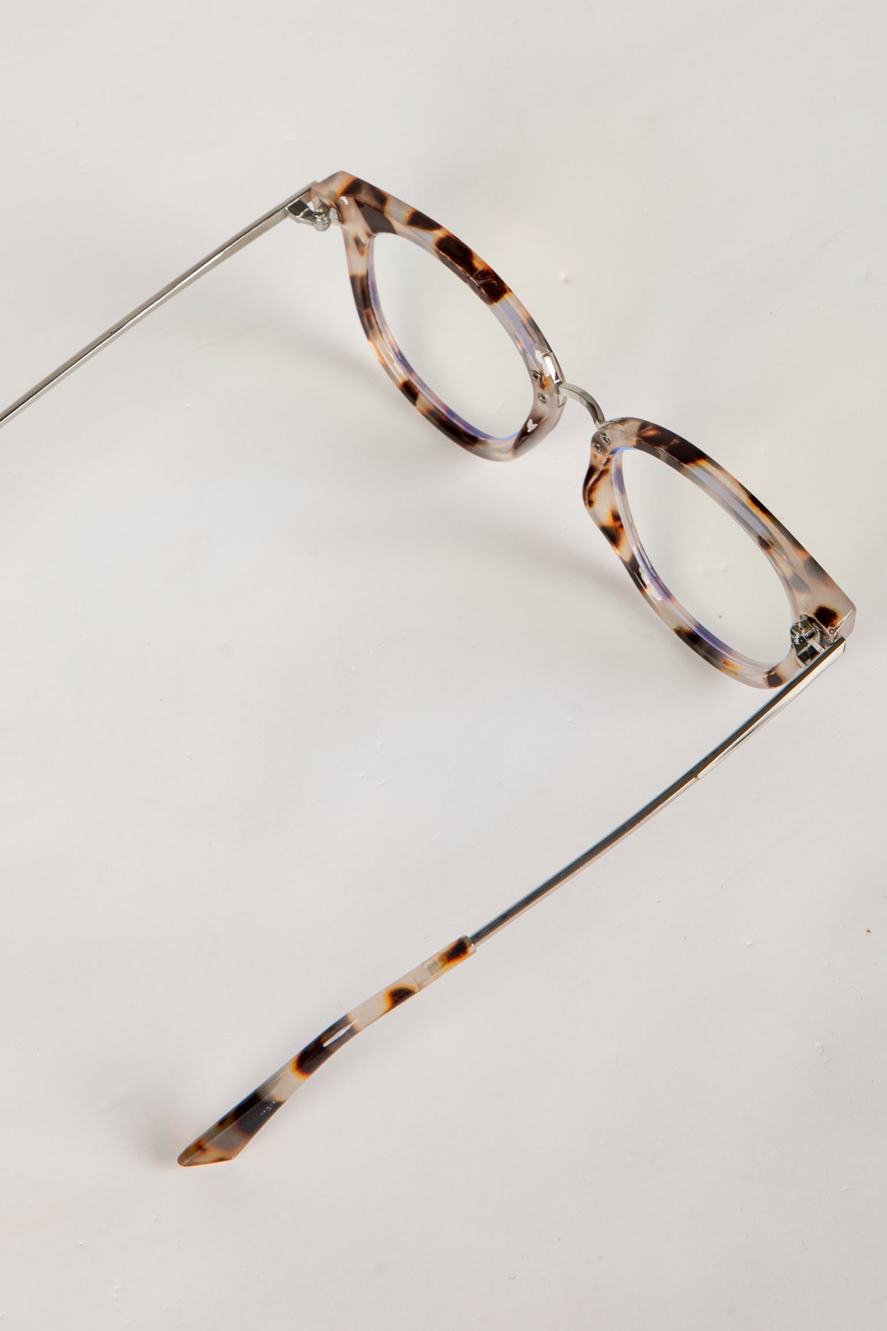 Pair of eyeglasses with tortoiseshell frame on a light gray background