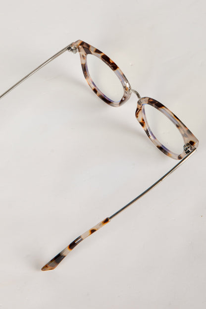 Pair of eyeglasses with tortoiseshell frame on a light gray background