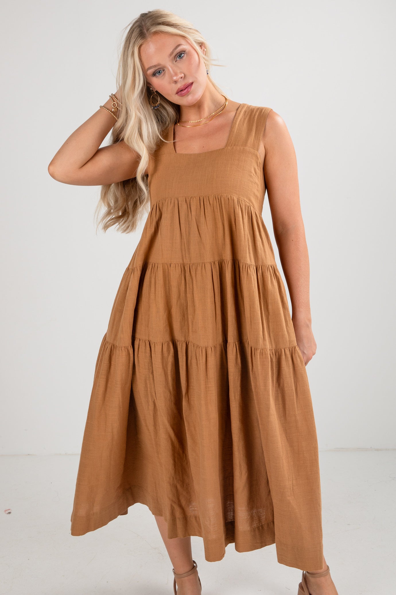 Woman wearing a brown tiered dress against a white background