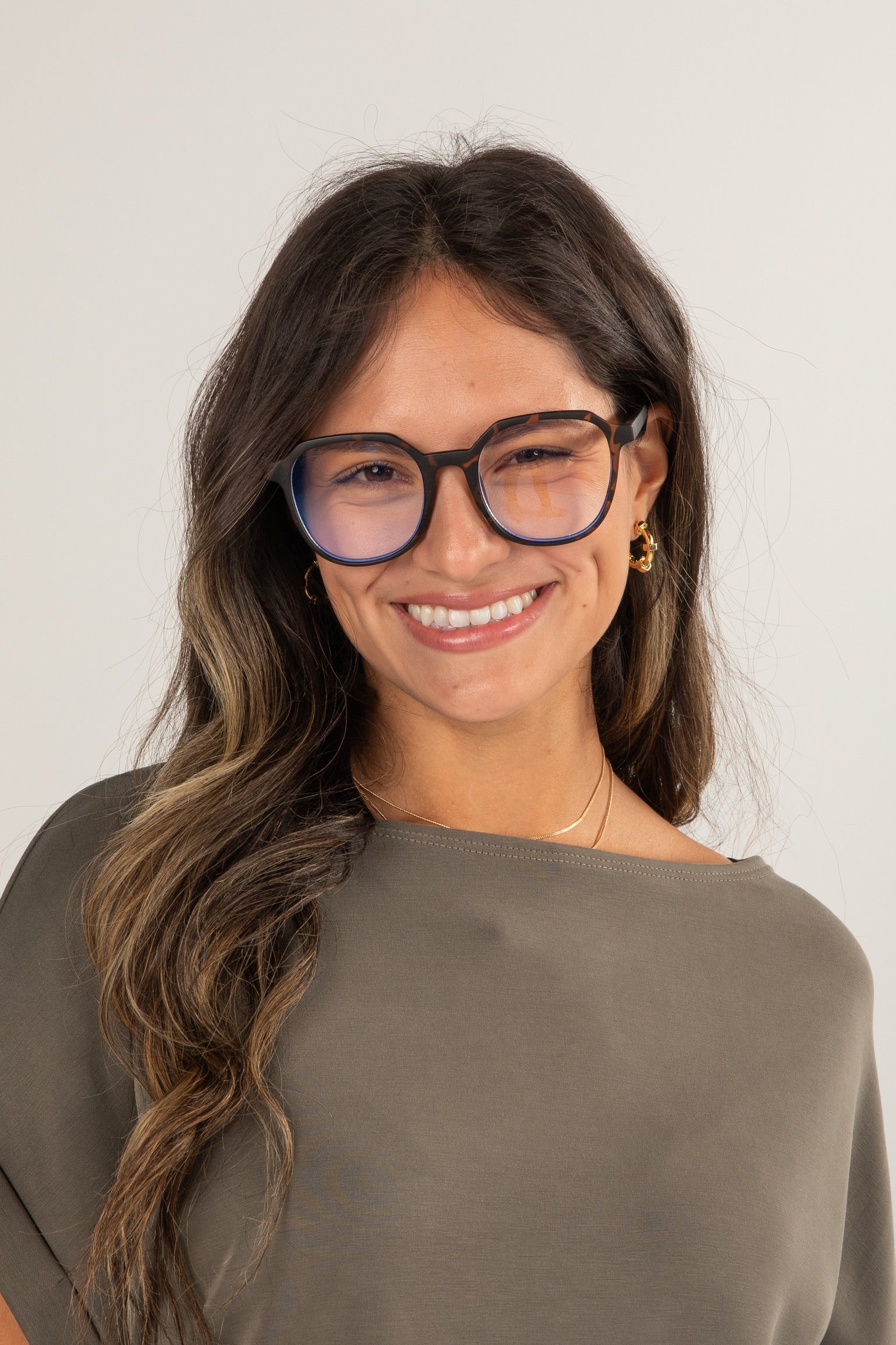 Woman wearing glasses and a green top against a plain background