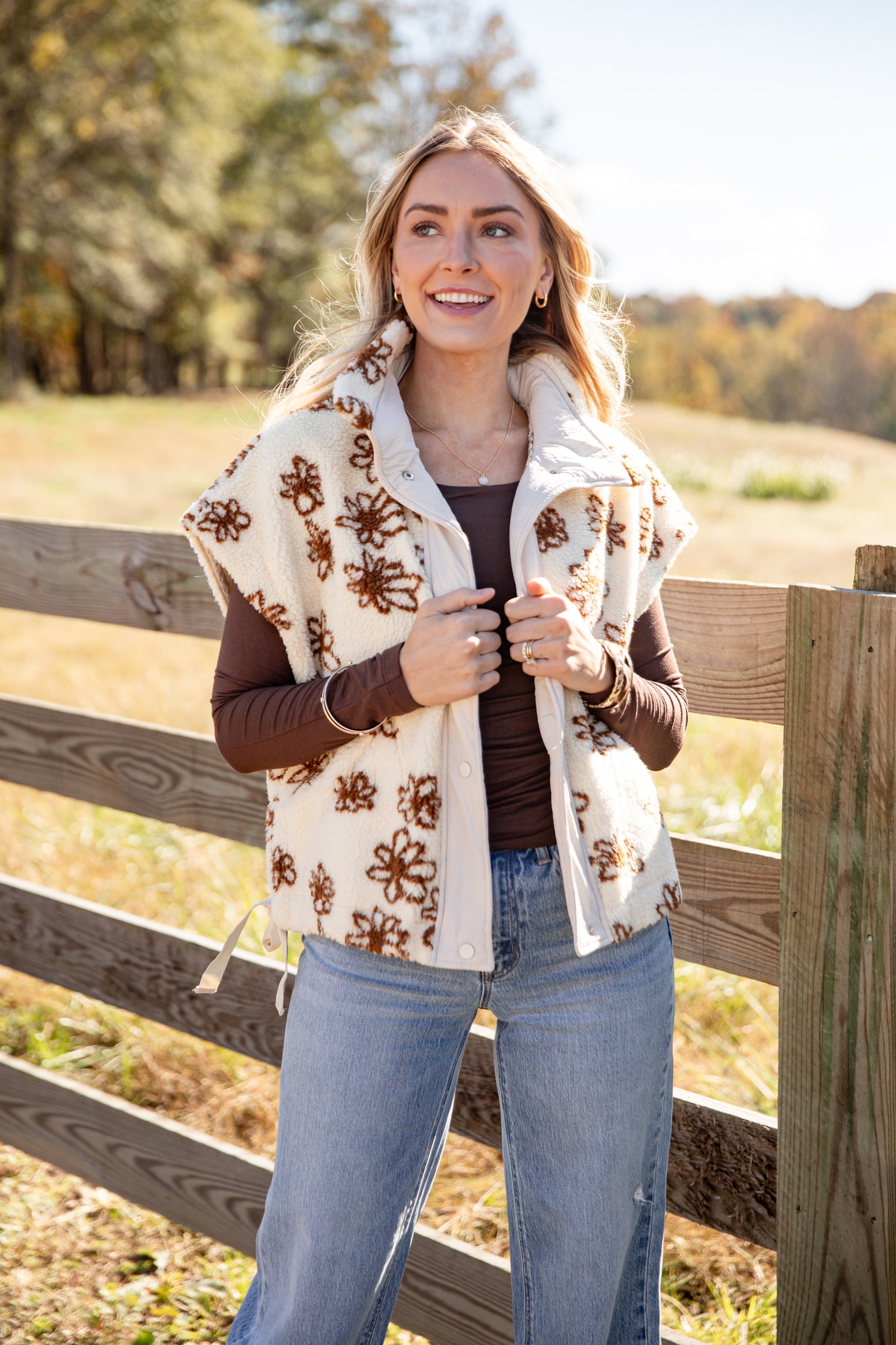 Woman wearing a patterned scarf standing in a field with trees in the background