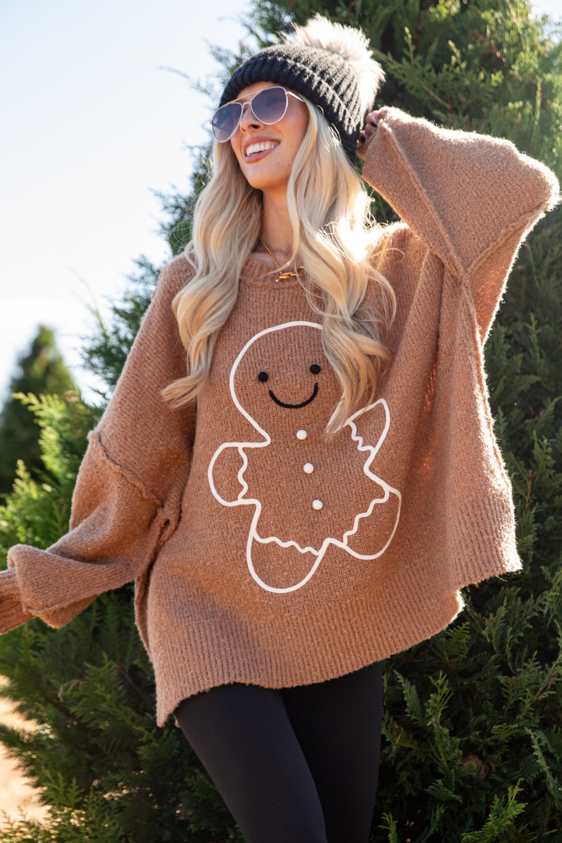 Person wearing a brown sweater with a gingerbread man design outdoors.