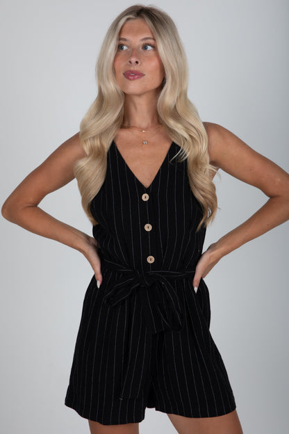 Woman wearing a black pinstripe romper against a plain background