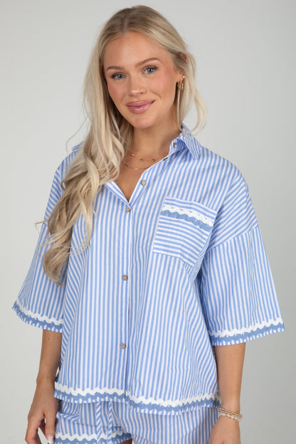 Woman wearing a blue and white striped shirt with matching pants on a gray background