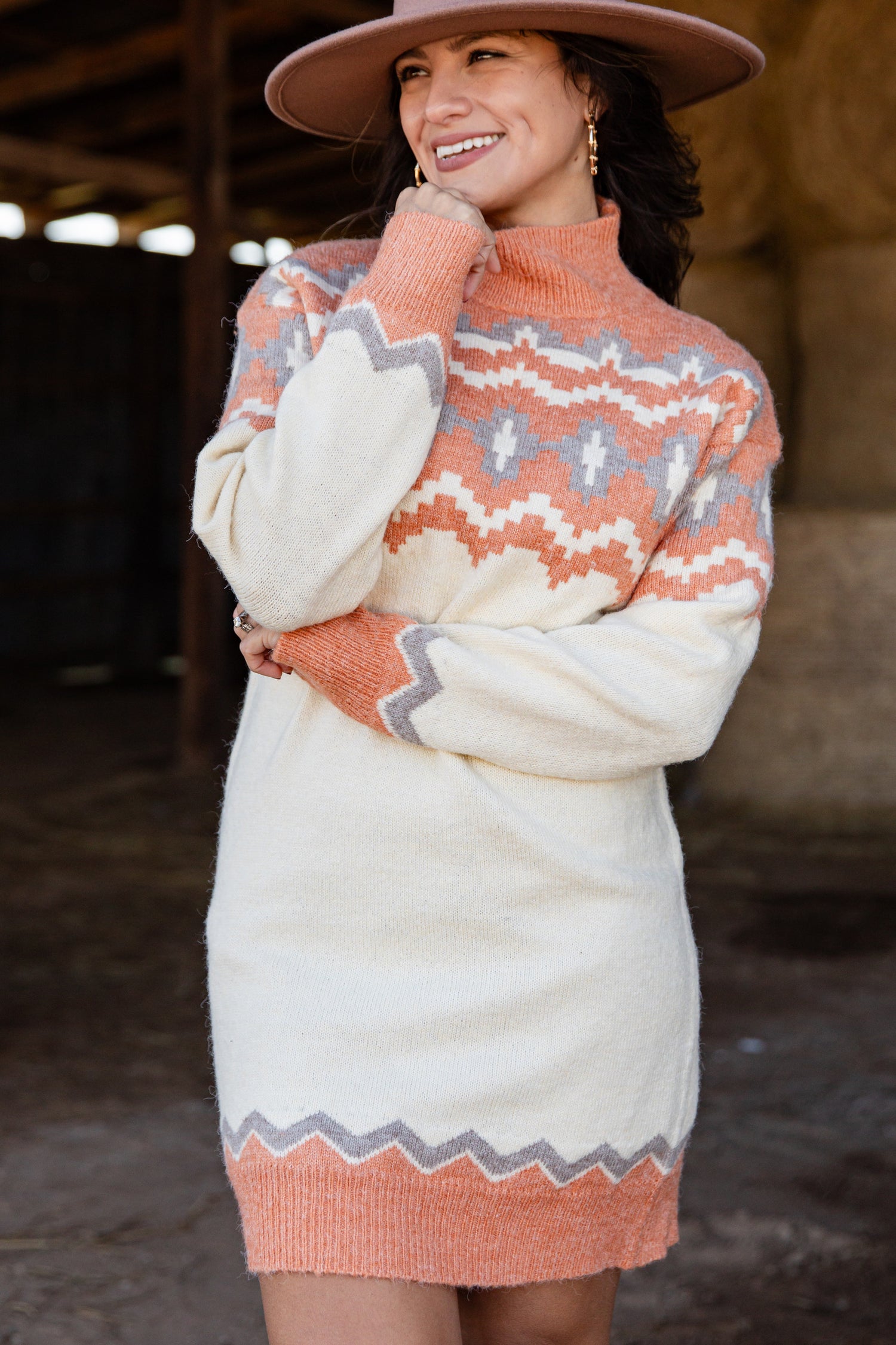 Woman wearing a patterned sweater dress with a hat in an indoor setting