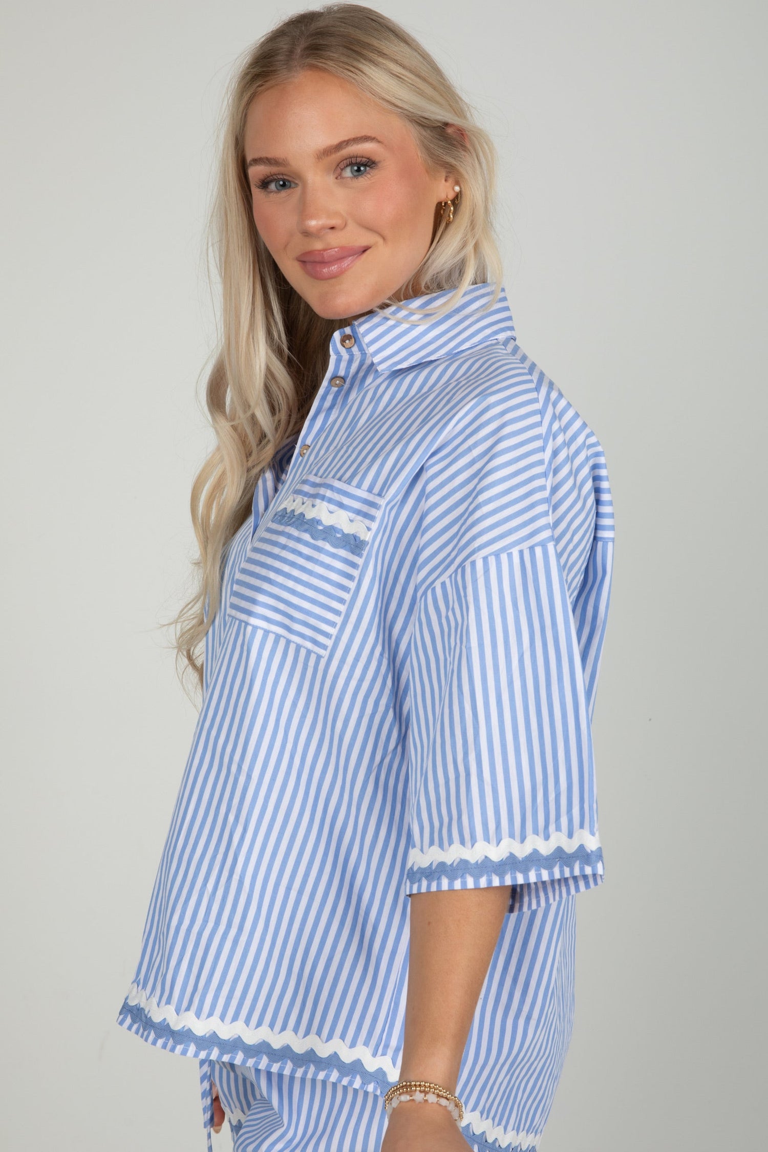 Woman wearing a blue and white striped shirt with a plain background
