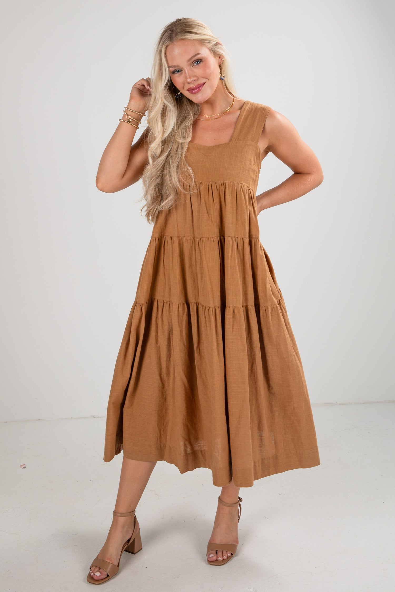 Woman wearing a brown tiered dress on a white background
