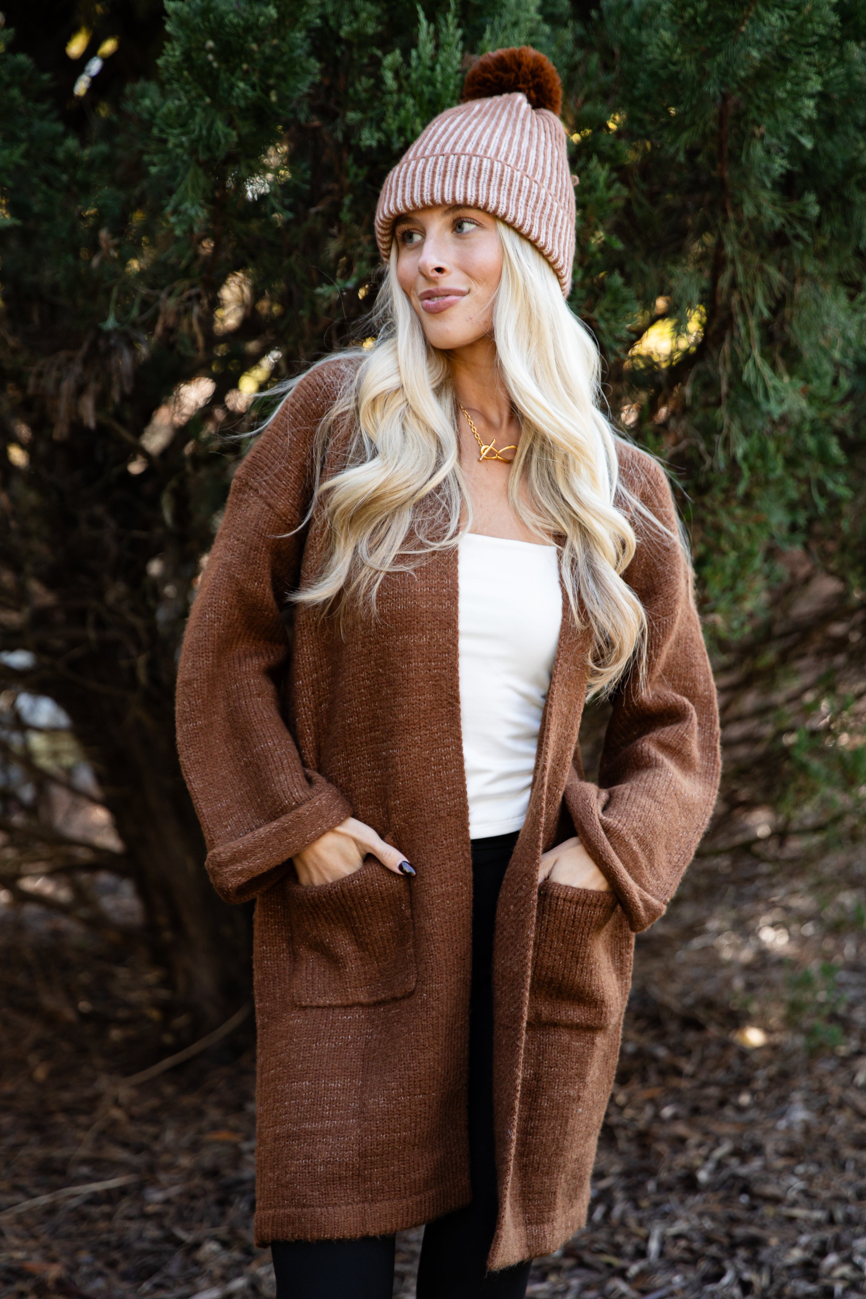 Woman wearing a brown coat and pink beanie outdoors