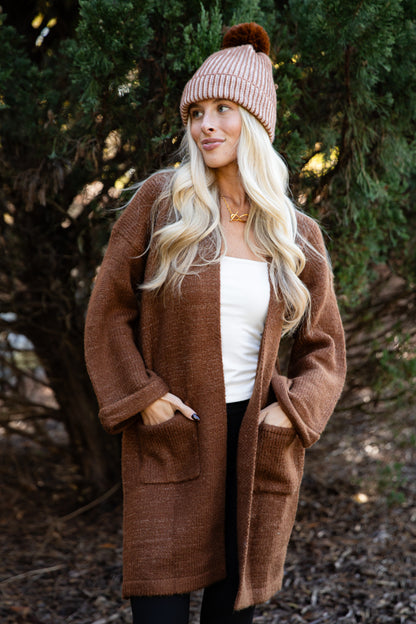 Woman wearing a brown coat and pink beanie outdoors