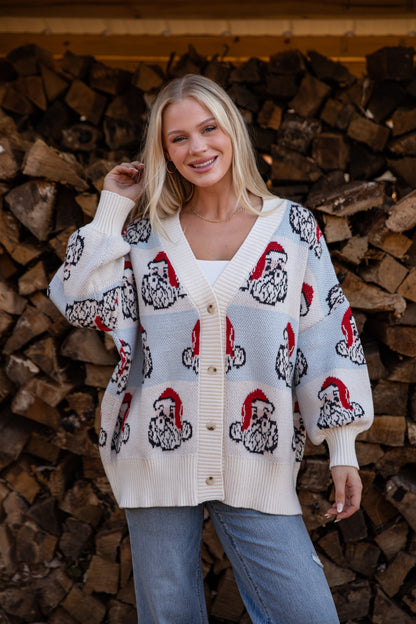 Woman wearing a patterned cardigan standing in front of stacked firewood.
