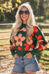 Woman wearing a colorful floral sweater and denim shorts outdoors.