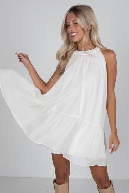 Woman wearing a white dress and beige boots on a plain background