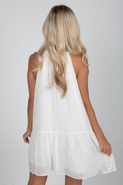 White sleeveless dress worn by a person with long blonde hair on a plain background