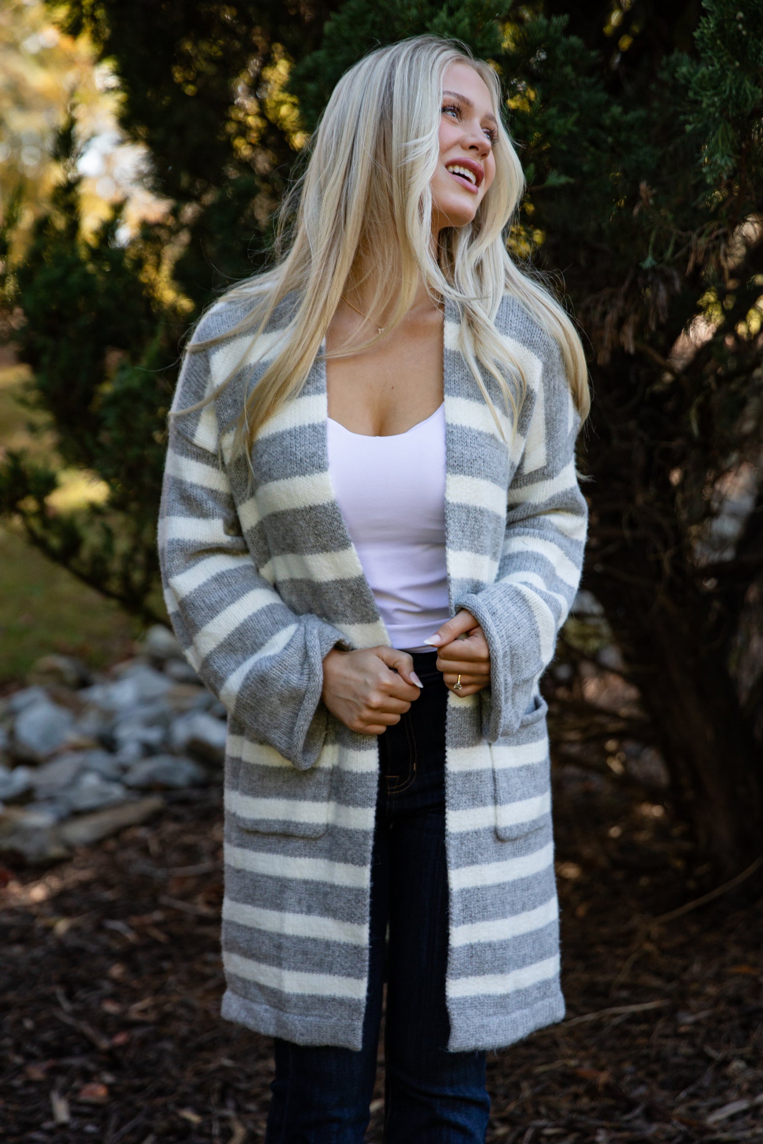 Woman wearing a long, striped cardigan in an outdoor setting