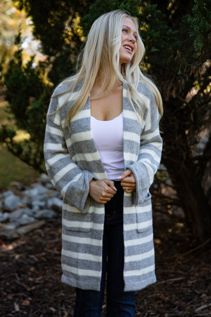 Woman wearing a long, striped cardigan in an outdoor setting