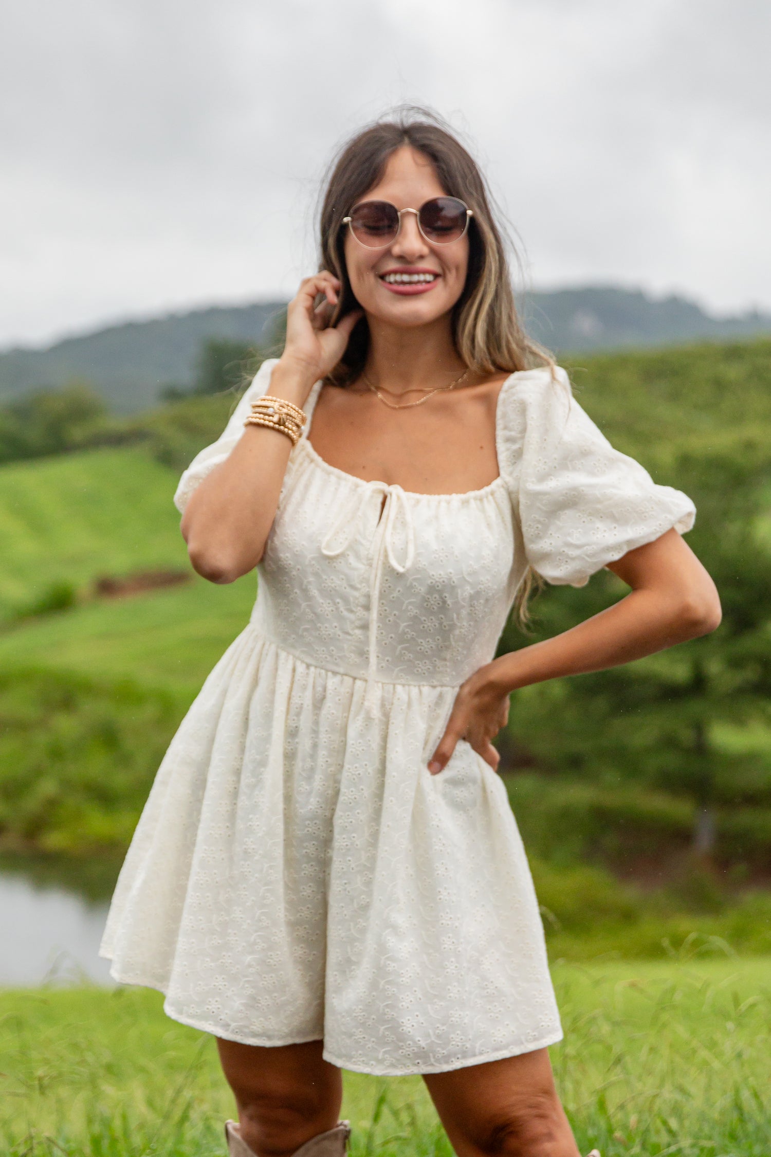 Woman in a white dress standing outdoors with greenery in the background
