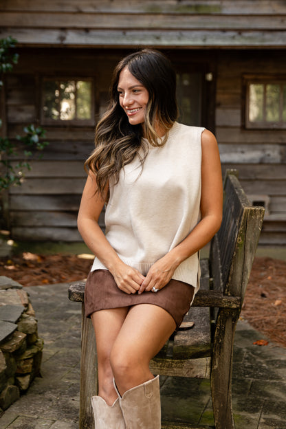 Woman sitting on a wooden bench outdoors with a rustic cabin in the background